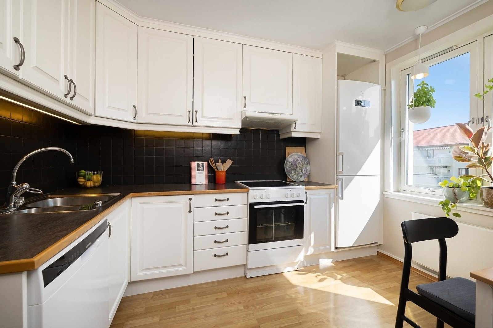 Kjøkkeninnredning med hvite, profilerte fronter fra 2001, benkeplate av laminat og nedfelt oppvaskkum i rustfritt stål med ett-greps armatur Galleribilde