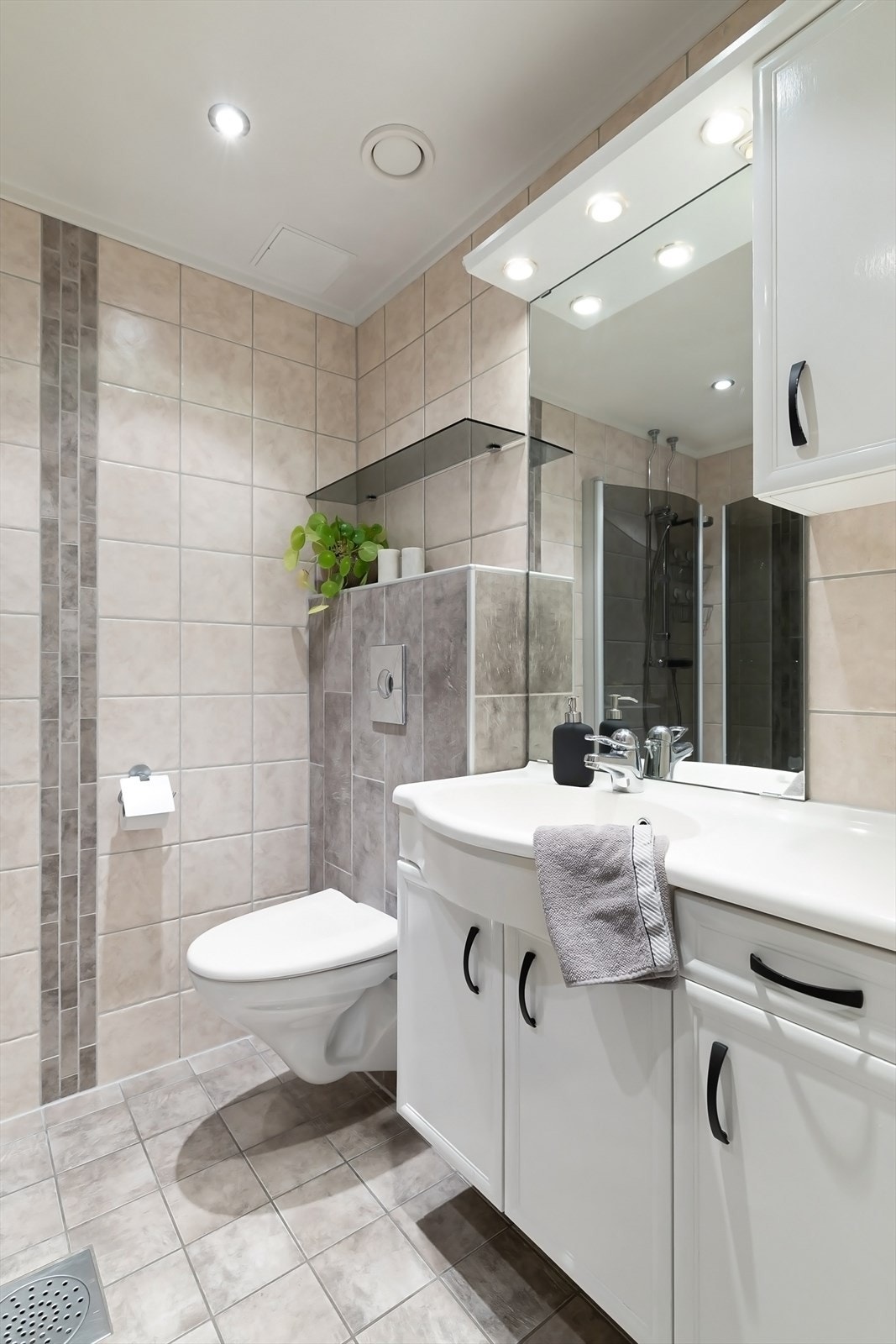 Baderomsinnredning med vegghengt servantskap, ovenpåliggende servant med ett-greps armatur, samt både speil og skap på vegg over servant Galleribilde