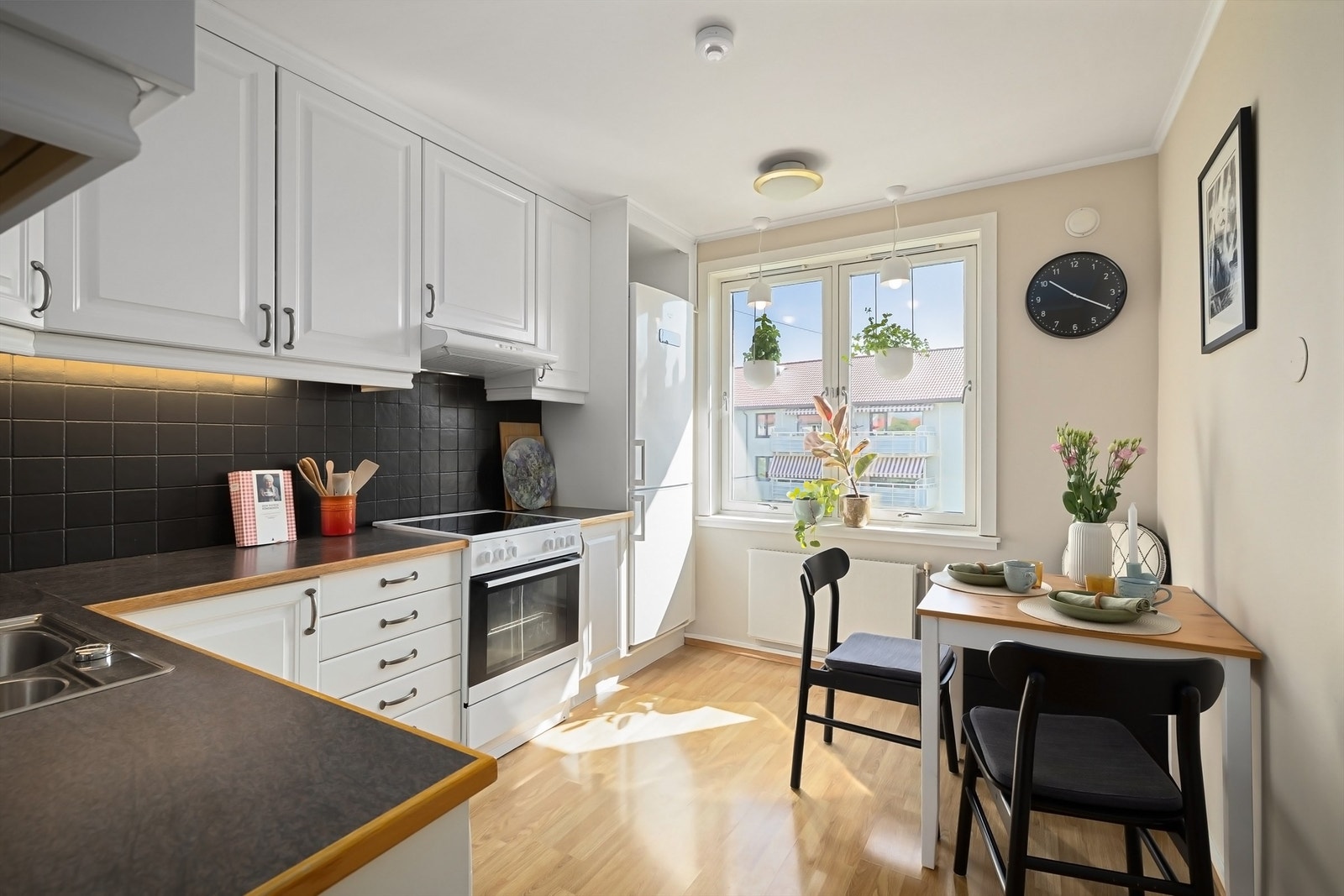 Kjøkkenet har frittstående hvitevarer som kjøleskap med frysedel, oppvaskmaskin og komfyr med kullfilterventilator plassert i overskap over Galleribilde