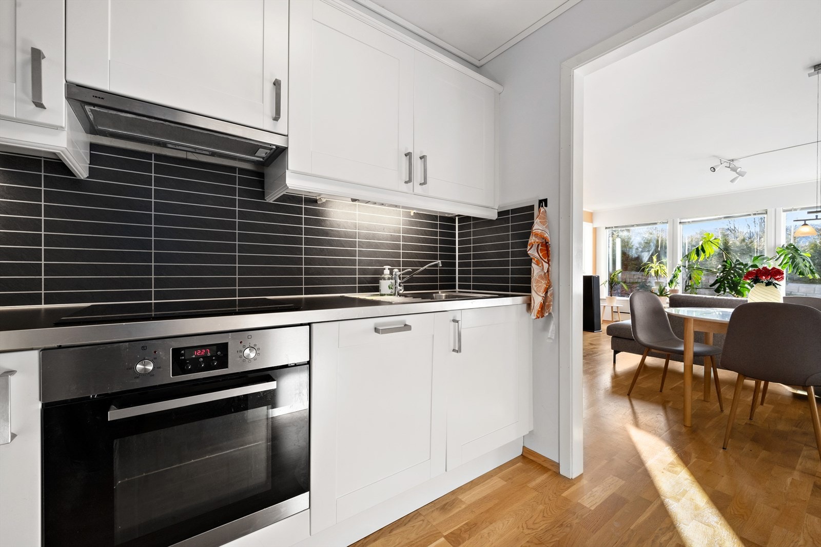 Kjøkkenet har innredning fra IKEA med profilerte lyse fronter, benkeplate av laminat med nedfelt vask og benkebeslag i stål. Galleribilde