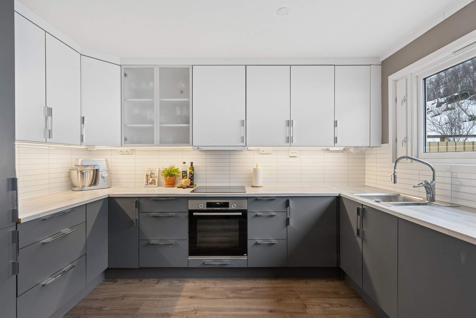 Flott kjøkken med integrerte hvitevarer som, komfyr, induksjonstopp, kjøleskap, oppvaskmaskin Galleribilde