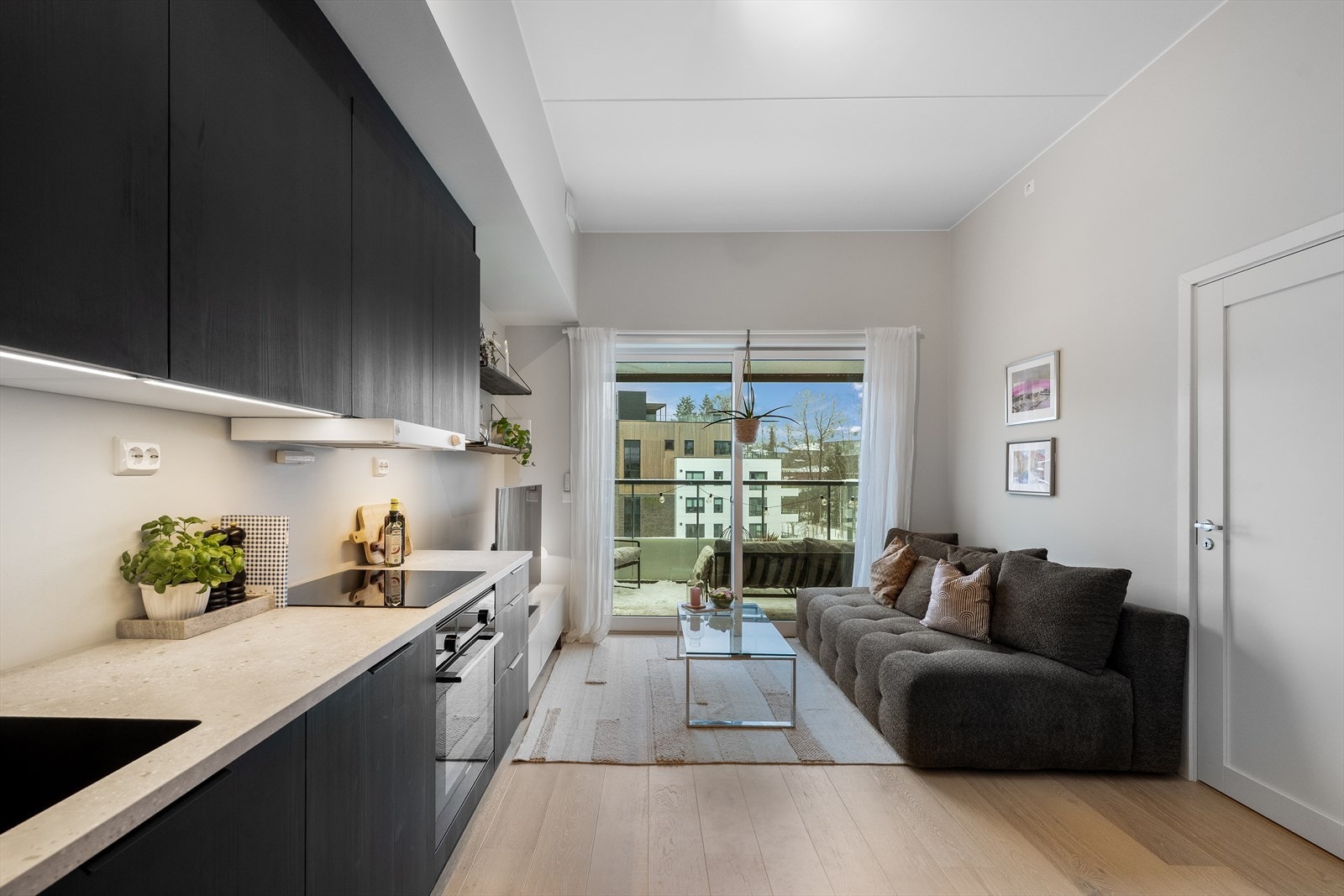 Åpen stue/ kjøkkenløsning med stilren kjøkkeinnredning med glatte mørke fronter og benkeplate i laminat. Galleribilde