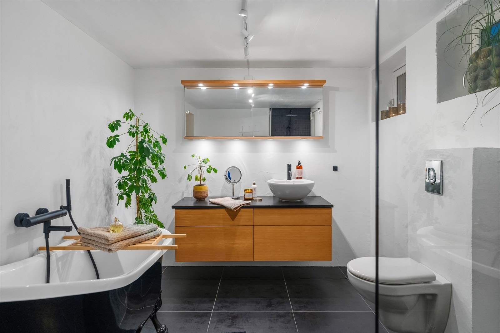 På badet er det både et dusjhjørne og et elegant badekar med dusjløsning, der førstnevnte har glassvegg, stor regnfallsdusj og sorte mosaikkfliser. Galleribilde