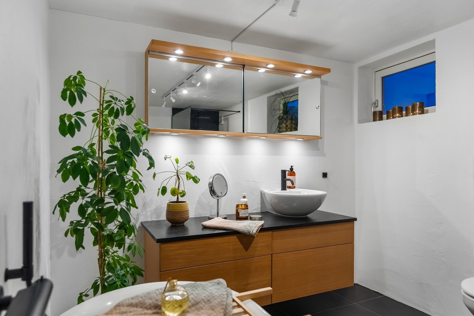 Badet i kjelleren er innredet med store, mørke gulvfliser og hvitmalte plater på veggene. Galleribilde