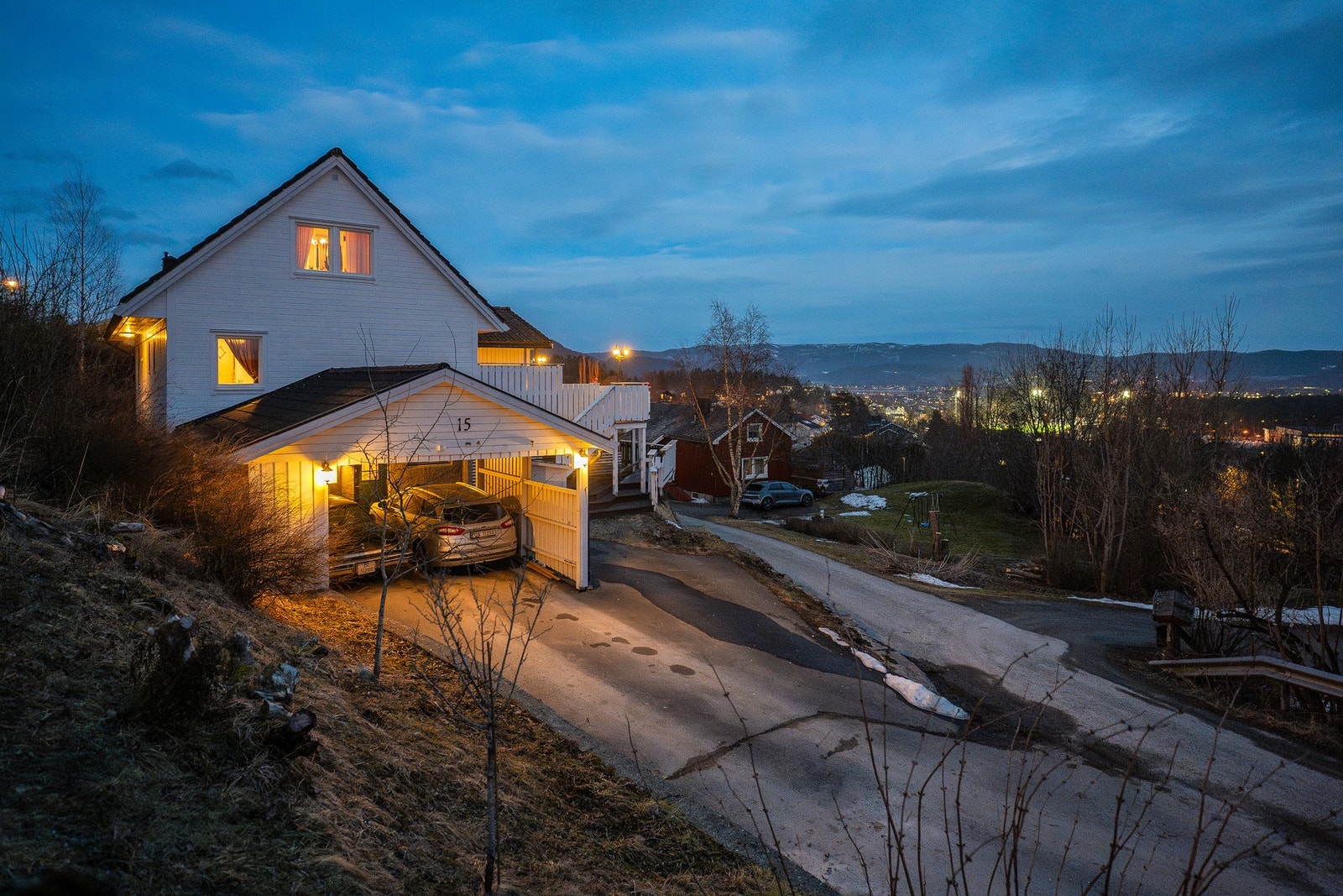 Asfaltert gårdsplass, dobbel carport og i tillegg en lite garasje integrert i sokkeletasje. Galleribilde