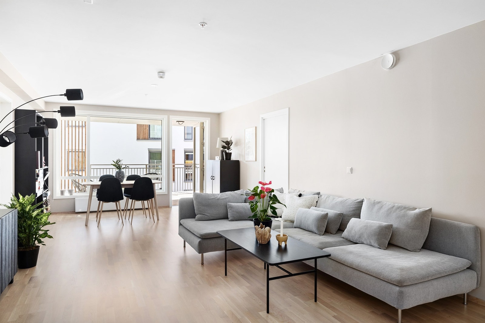 Åpen stue- og kjøkkenløsning. Leiligheten har hovedsakelig tre-stavs eikeparkett på gulv, vegger og himlinger med malte, slette flater. Slette innerdører. Foto: Christian Thorsbye - Diakrit Galleribilde