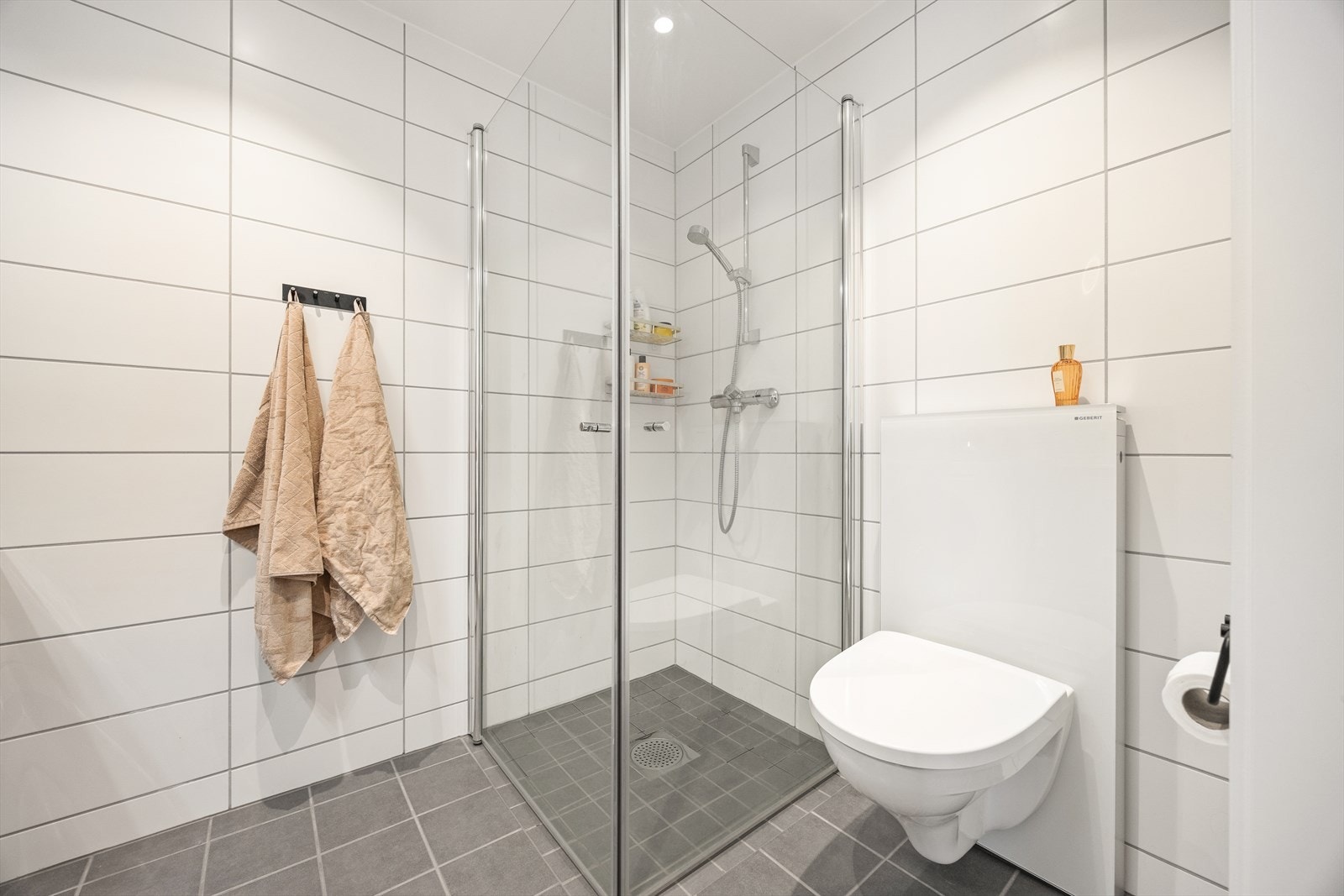 Dusjhjørne med innfellbare glassdører og vegghengt toalett gir et romslig inntrykk. Galleribilde