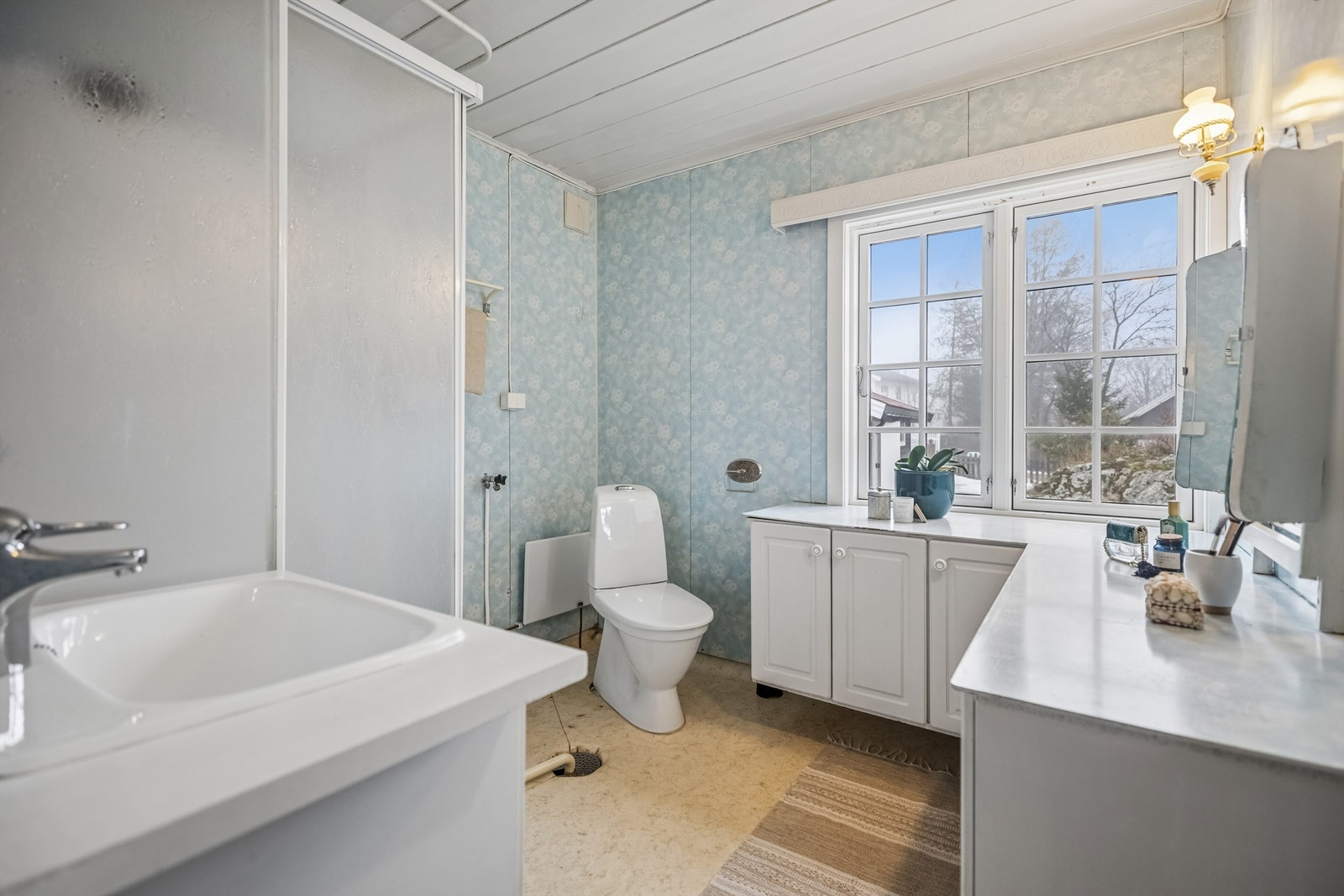 Eldre bad med dusjkabinett, servantinnredning, gulvstående toalett og opplegg for vaskemaskin. Galleribilde