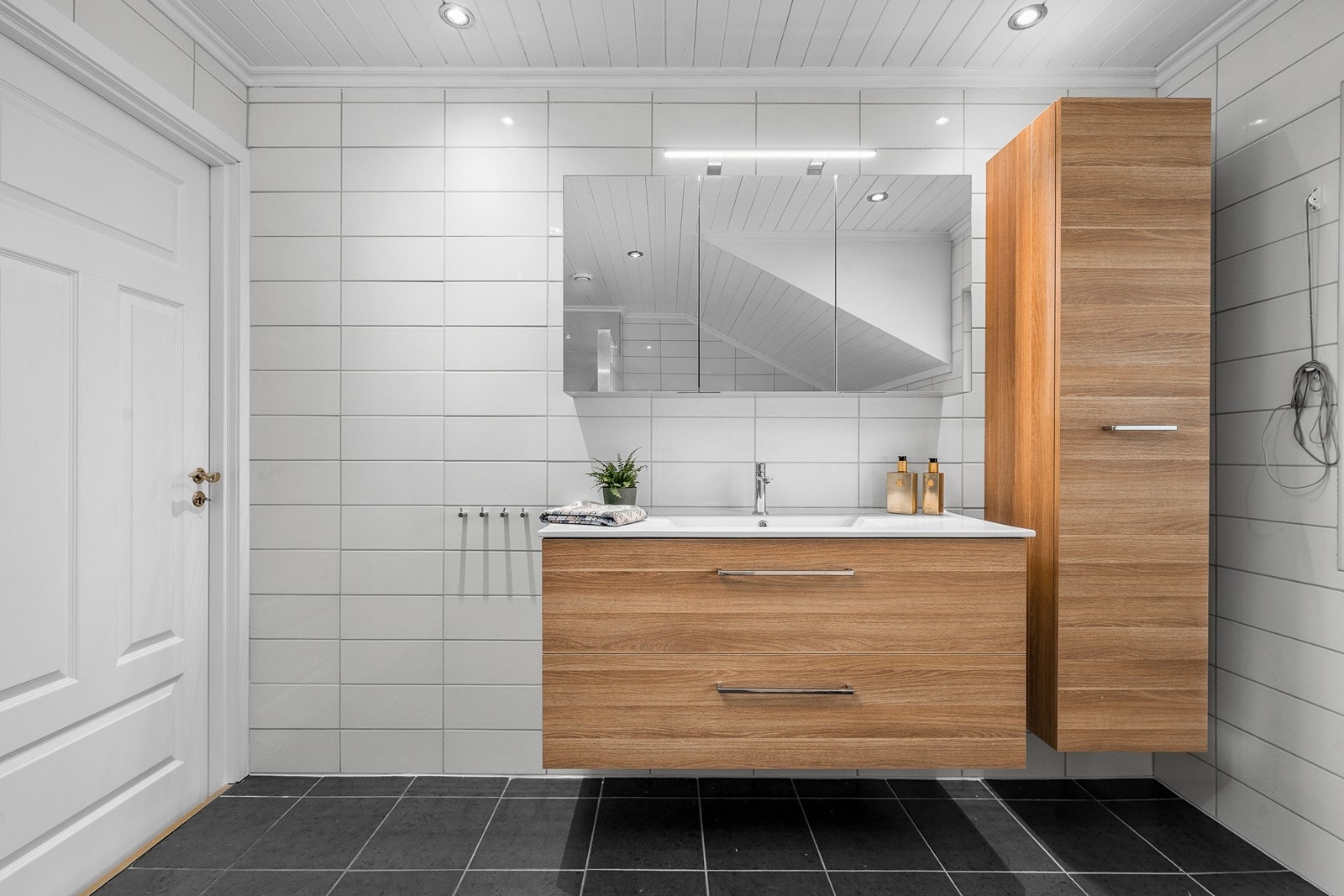 Baderomsinnredning fra Dansani med servant og speilskap, samt et praktisk høyskap for ekstra oppbevaring. Galleribilde