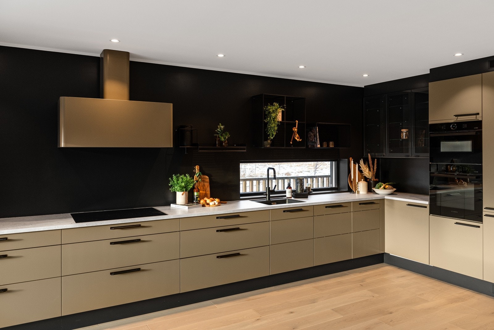 Vegger er malt i en sort og trendy farge som står i stil til sideskapene og hylleløsningen til kjøkkeninnredninge Galleribilde