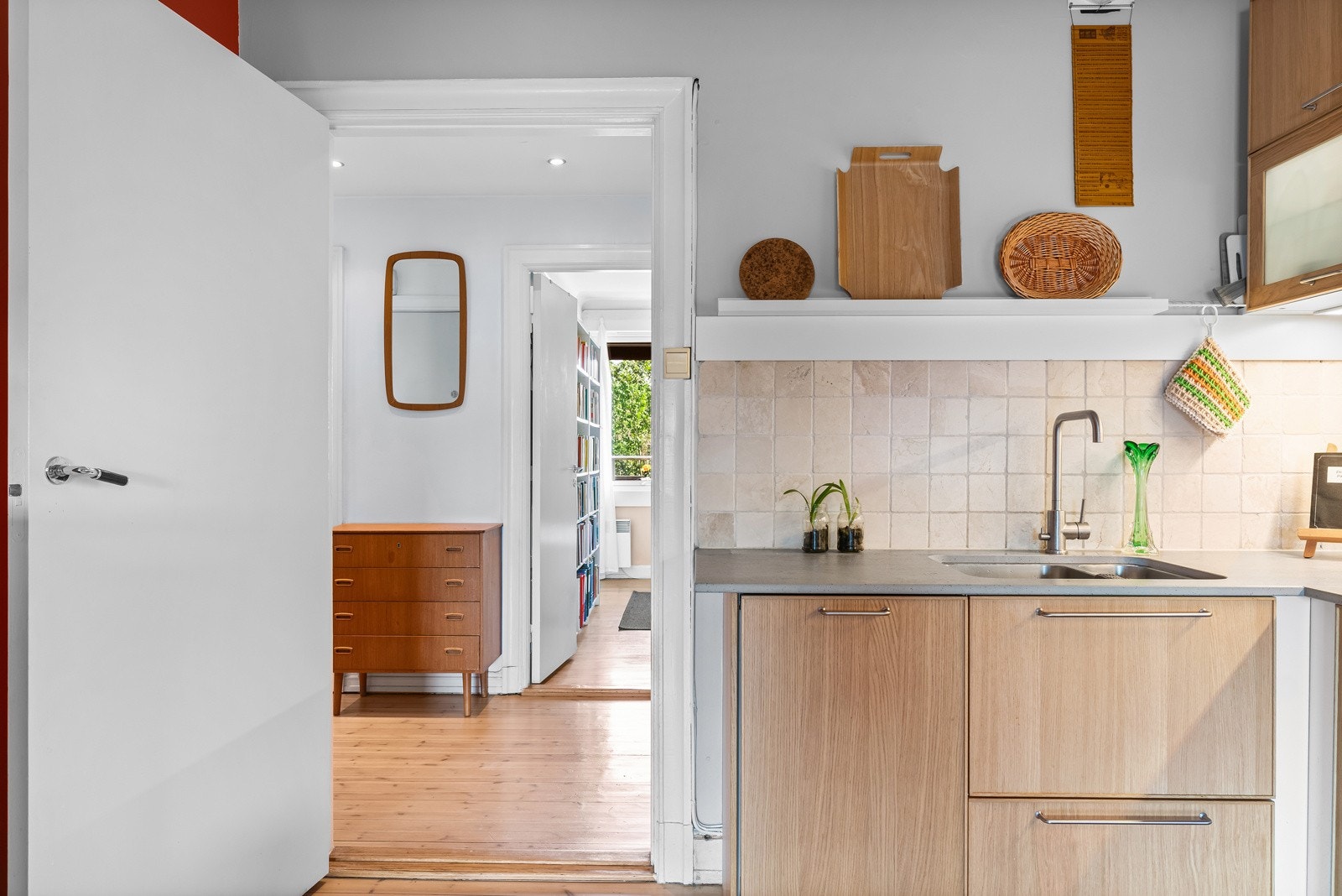 Det er flisfelt mellom benkeplate og overskap, og integrert platetopp, stekeovn, mikrobølgeovn og oppvaskmaskin. Galleribilde