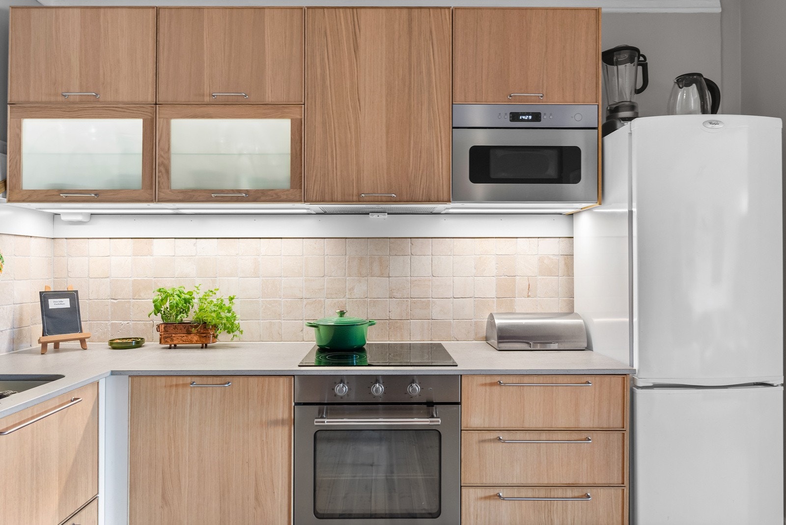 Kjøkkeninnredning med fronter av typen Ekestad i lys eik og vitrinedører med frostet glass. Galleribilde