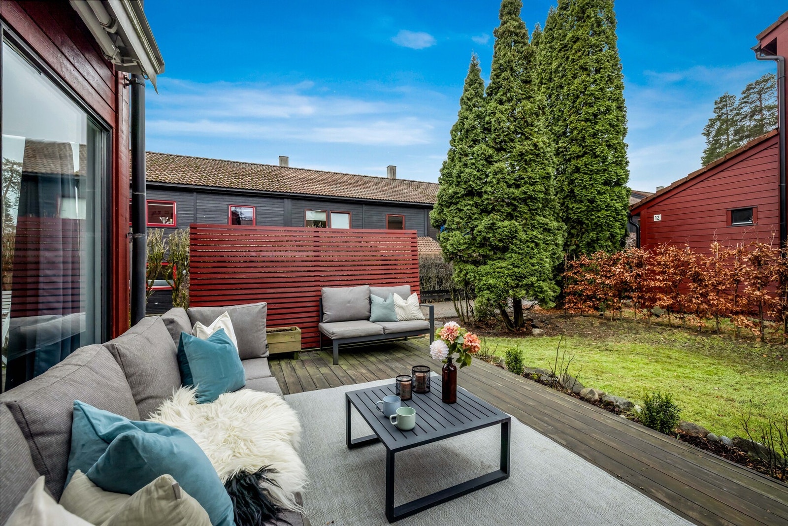 Hagen omkranses av hekk og er ellers beplantet med plen, prydsbusker og frodige blomsterbed Galleribilde