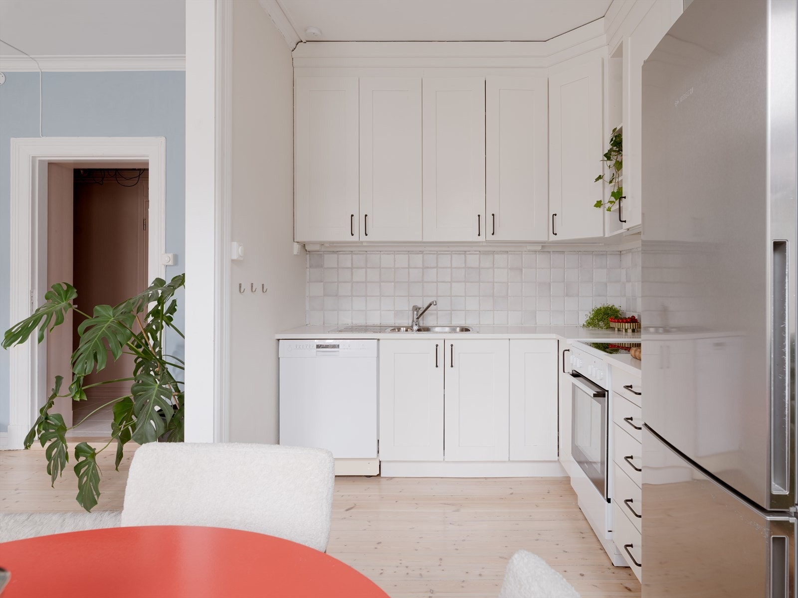 Kjøkkenet har en tidløs innredning med malte fronter, vitrineskap og fliser over benken. Galleribilde