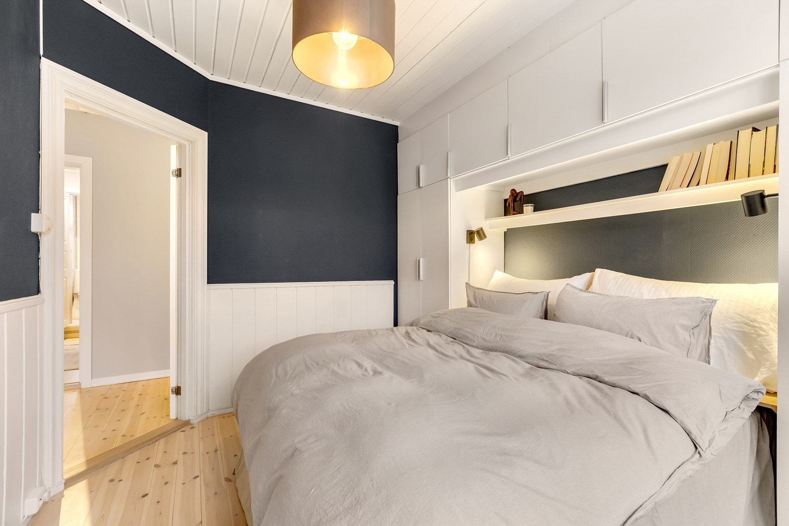 De rolige fargetonene og den smarte garderobeløsningen rundt sengen gir rommet et ryddig og helhetlig preg. Galleribilde