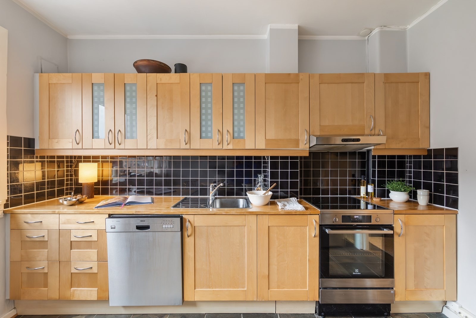 Benkeplaten er av heltre med en nedfelt vaskekum i rustfritt stål og belysning over benkeplaten. Galleribilde