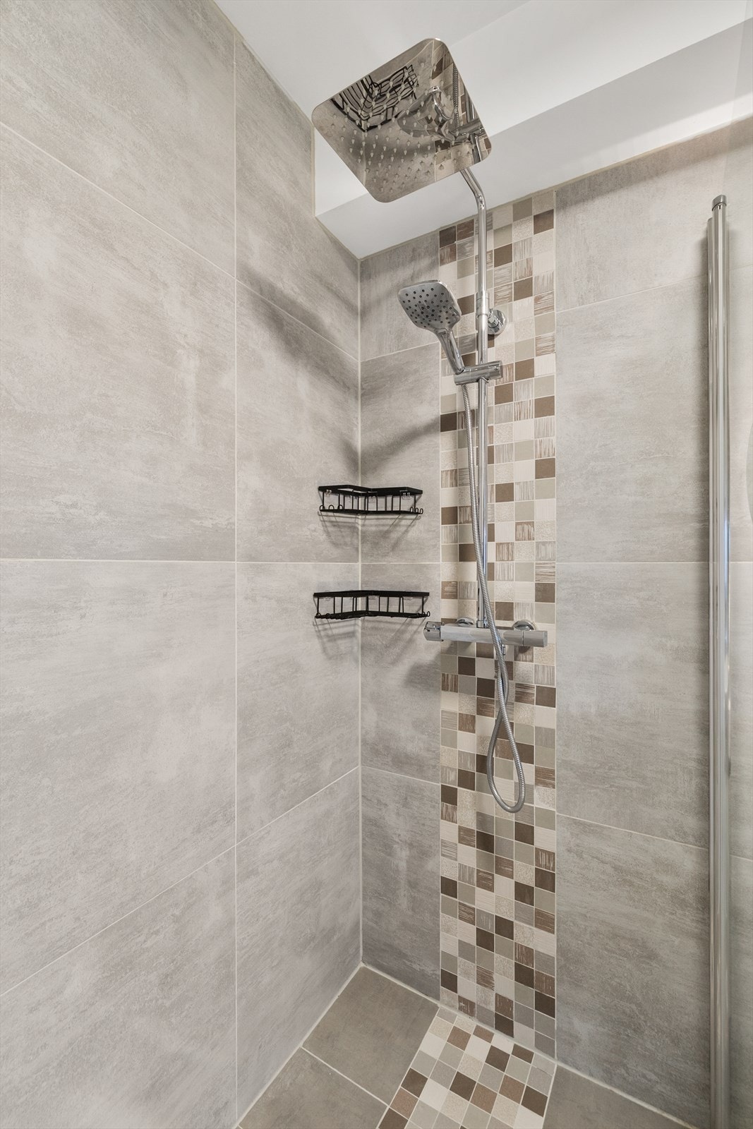 Dekorative mosaikkfliser i dusjsonen gir badet et personlig preg. Galleribilde