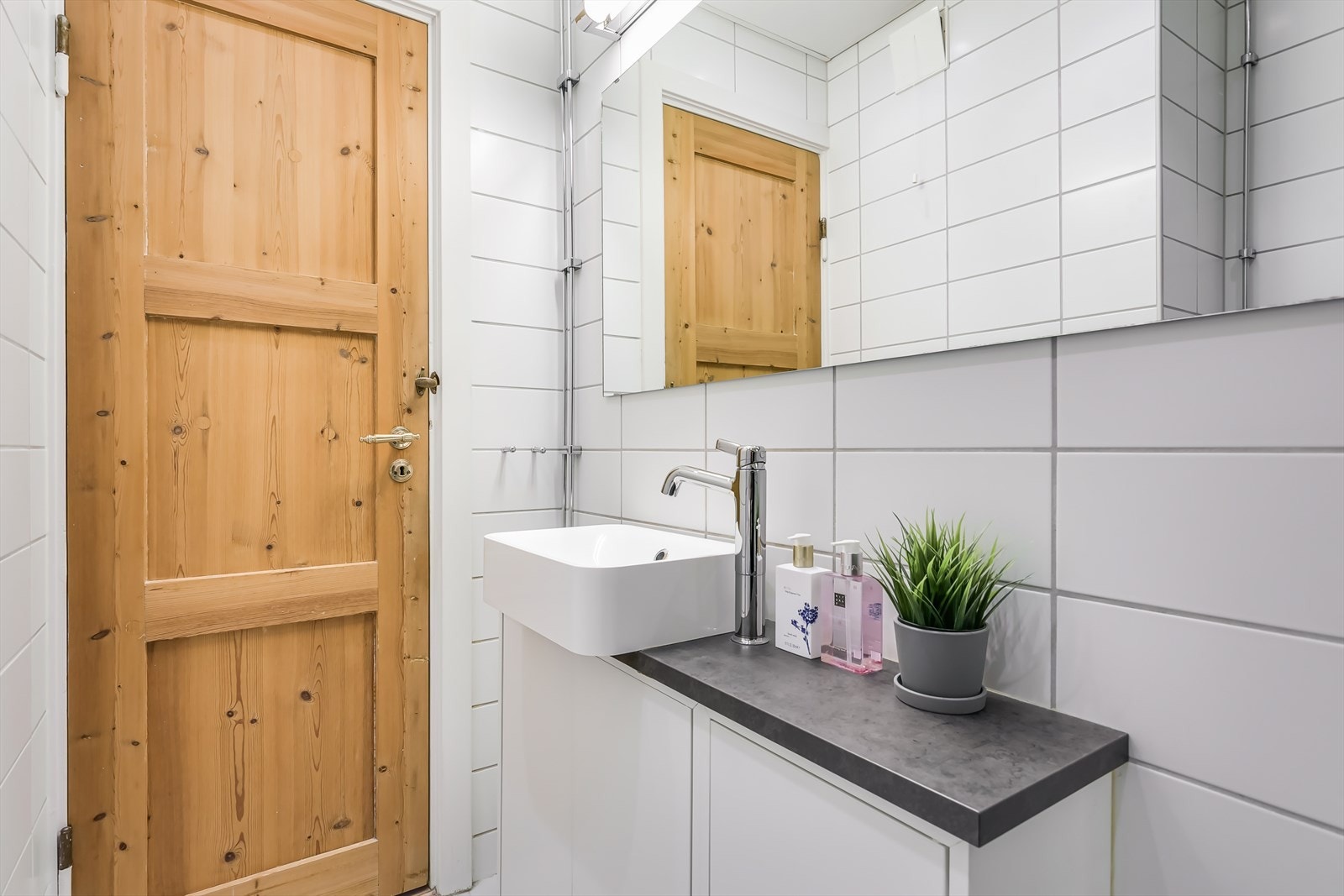 Badet er innredet med underskap med toppmontert servant, gulvmontert toalett,dusjhjørne med svingbare glassdører og opplegg for vaskemaskin. Galleribilde