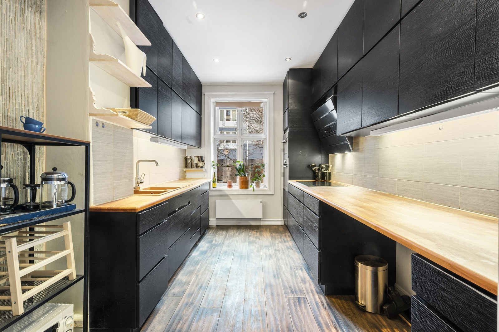 Praktisk og arealeffektivt kjøkken med rikelig benke- og skapplass på begge sider. Det er 2 integrerte stekeovner, fire-soners induksjons koketopp og oppvaskmaskin. Galleribilde