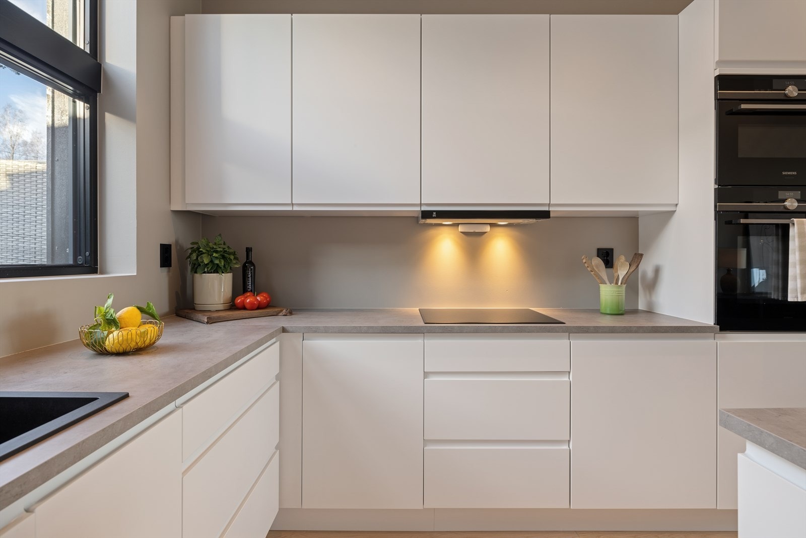 Kjøkkeninnredning med hvite glatte fronte, malte flater over benkeplate i laminat. Her er det også integrerte hvitevarer. Galleribilde