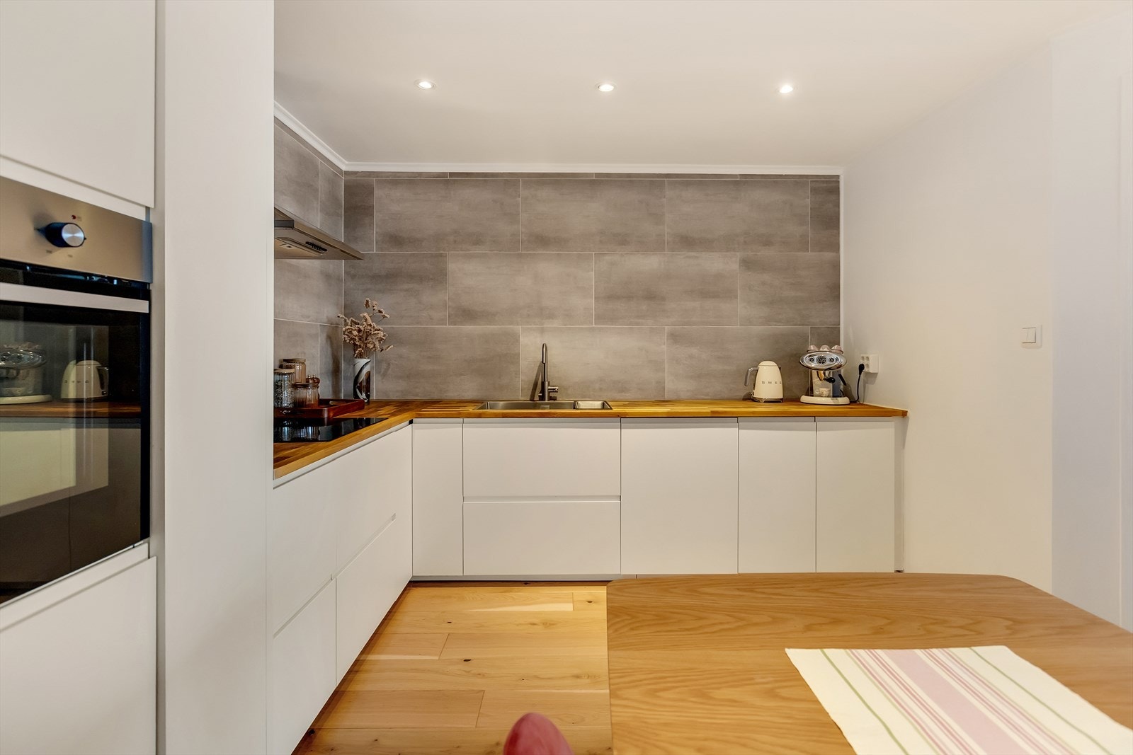 Kjøkkenet har innredning med glatte fronter. Benkeplaten er av heltre. Det er integrert kjøl/fryseskap, oppvaskmaskin, induksjonstopp og stekeovn. Galleribilde