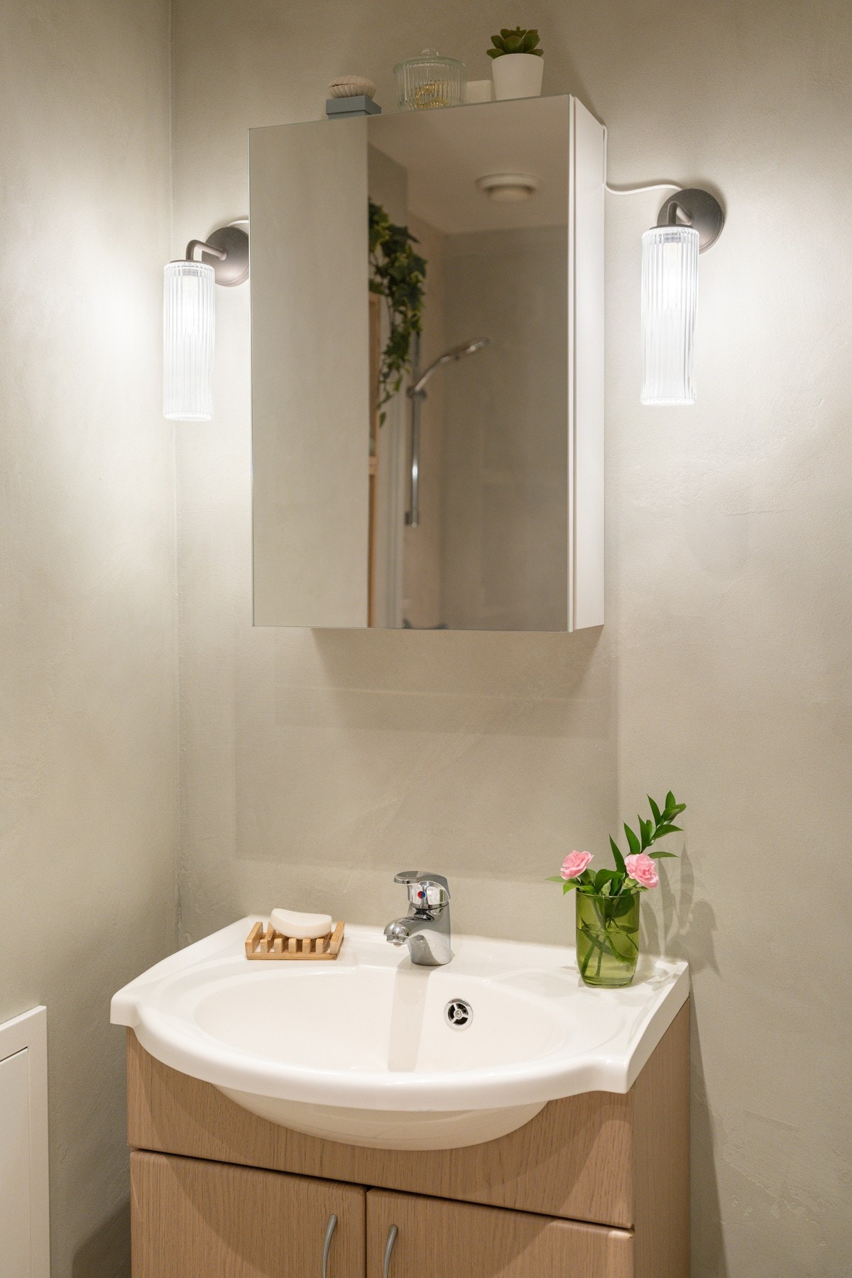 Pen baderomsinnredning med ovenpåliggende servant, speilskap og vegghengt belysning over. Galleribilde