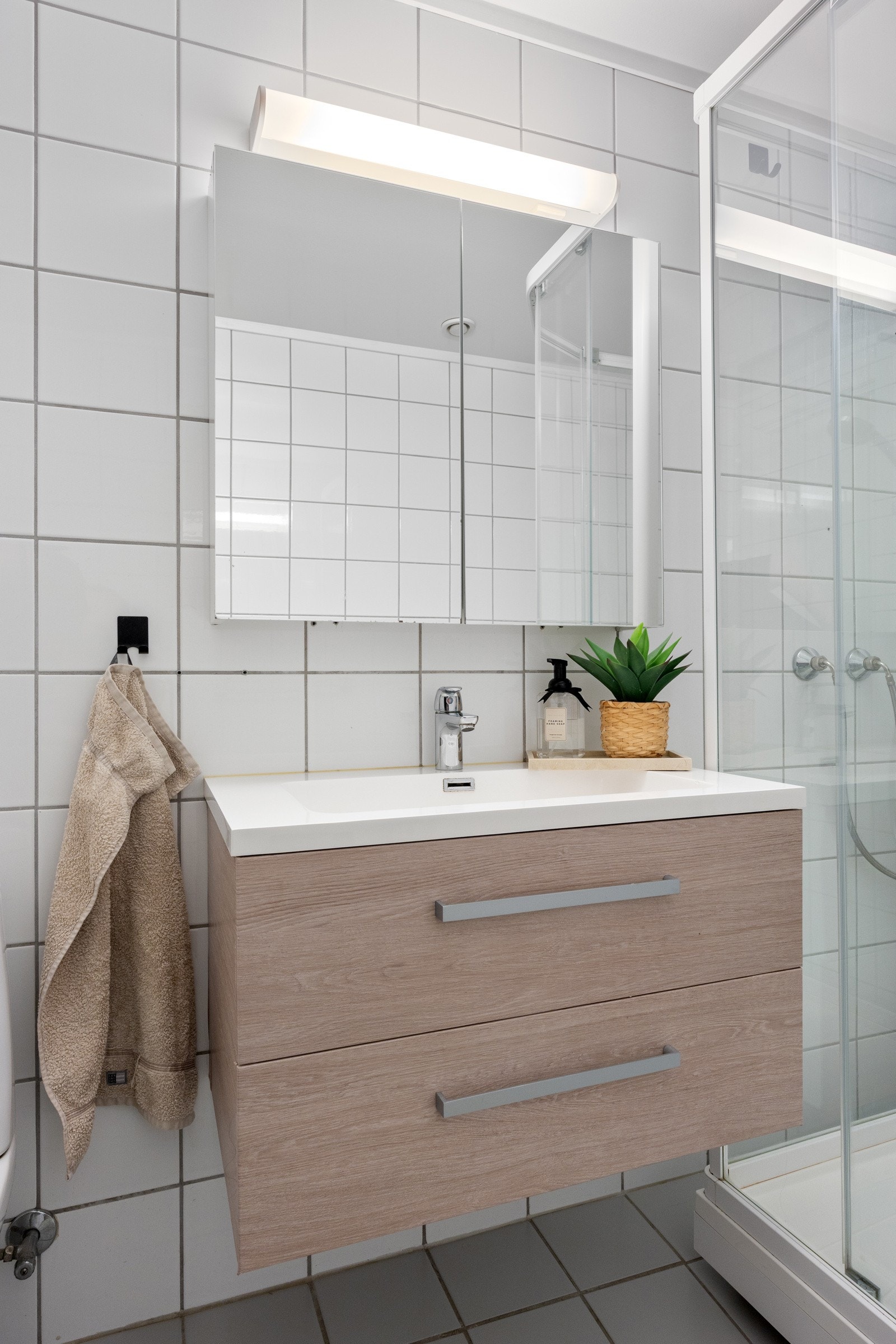 Badet har en vegghengt servantinnredning med ovenpåliggende servant og armatur, samt speilskap med overlys. Galleribilde