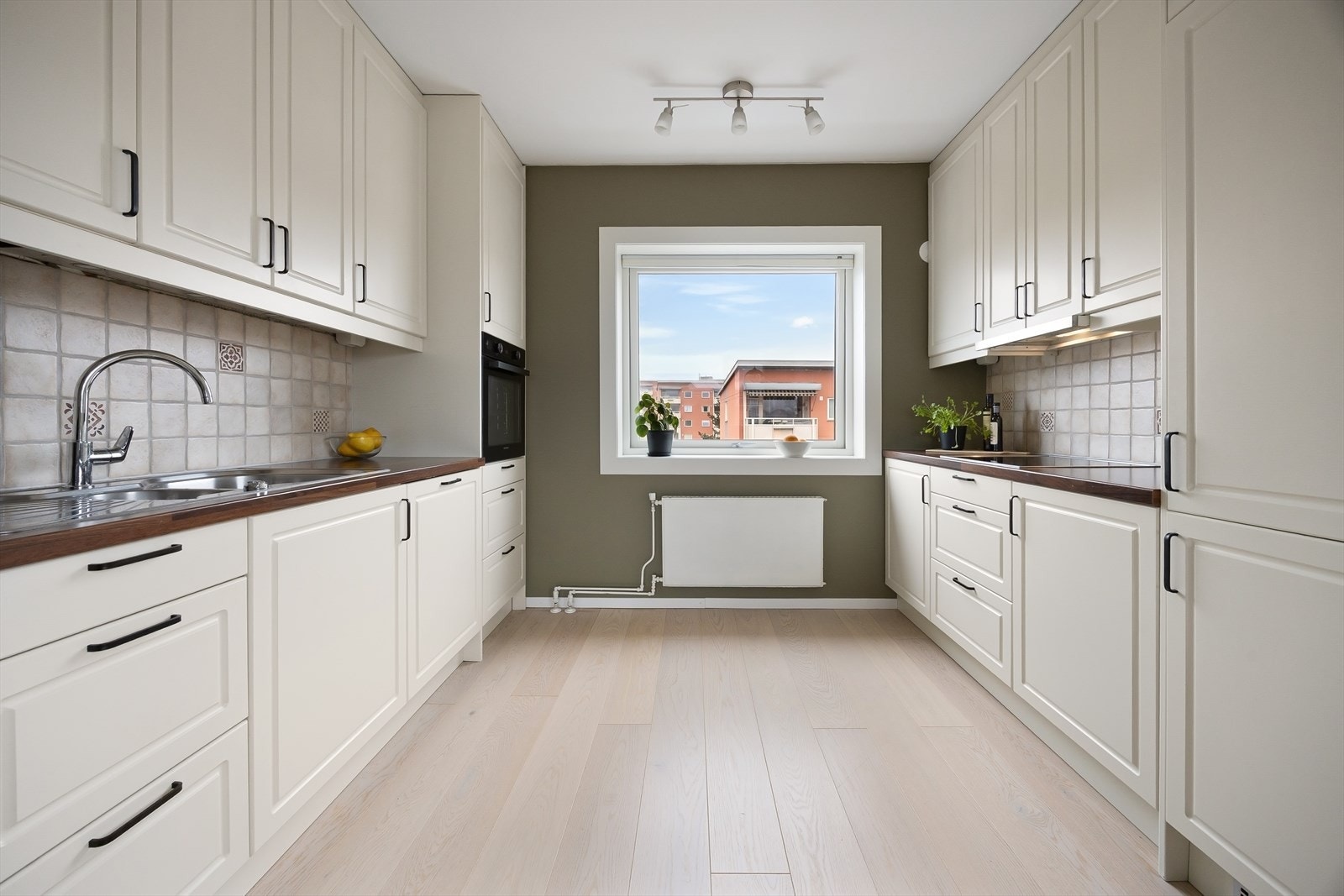 Kjøkkeninnredning med profilerte fronter, laminat benkeplate, induksjonstopp, samt integrert kjøleskap/fryser, komfyr og oppvaskmaskin. Galleribilde