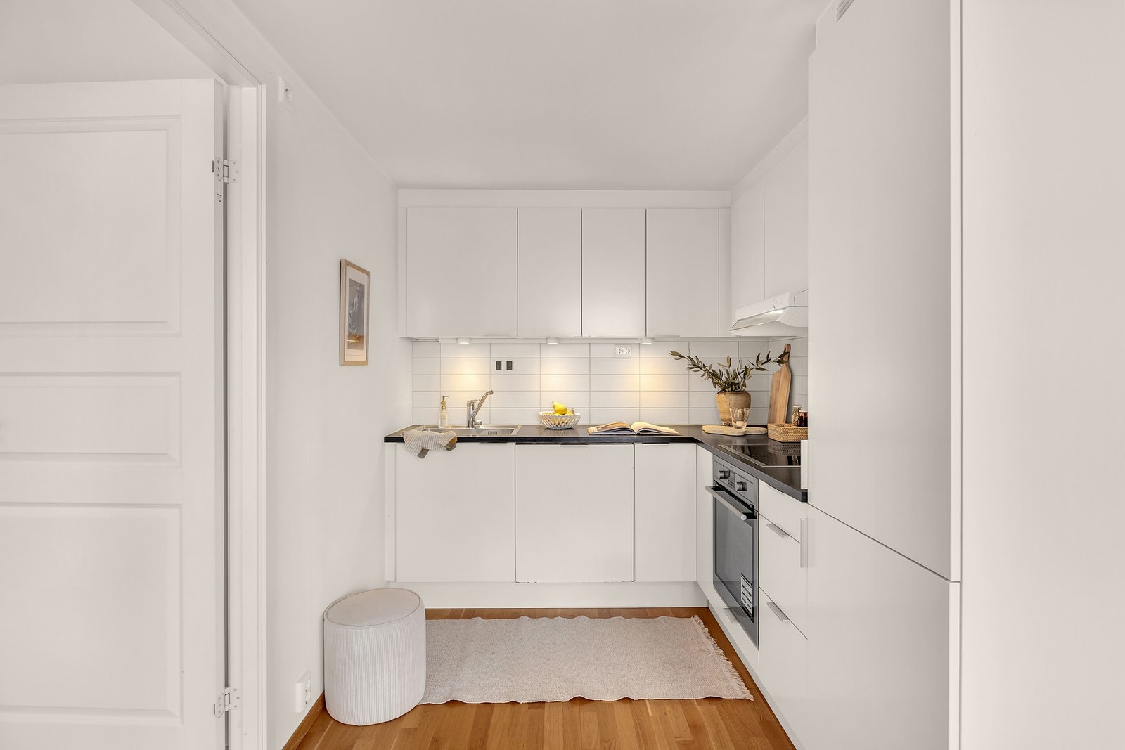 Kjøkkenet har innredning med glatte fronter, benkeplaten er av
laminat og enkel stålkum med ettgreps blandebatteri. Det er
kjøl/fryseskap, oppvaskmaskin, komfyr, platetopp, vannstoppsystem
og komfyrvakt. Galleribilde