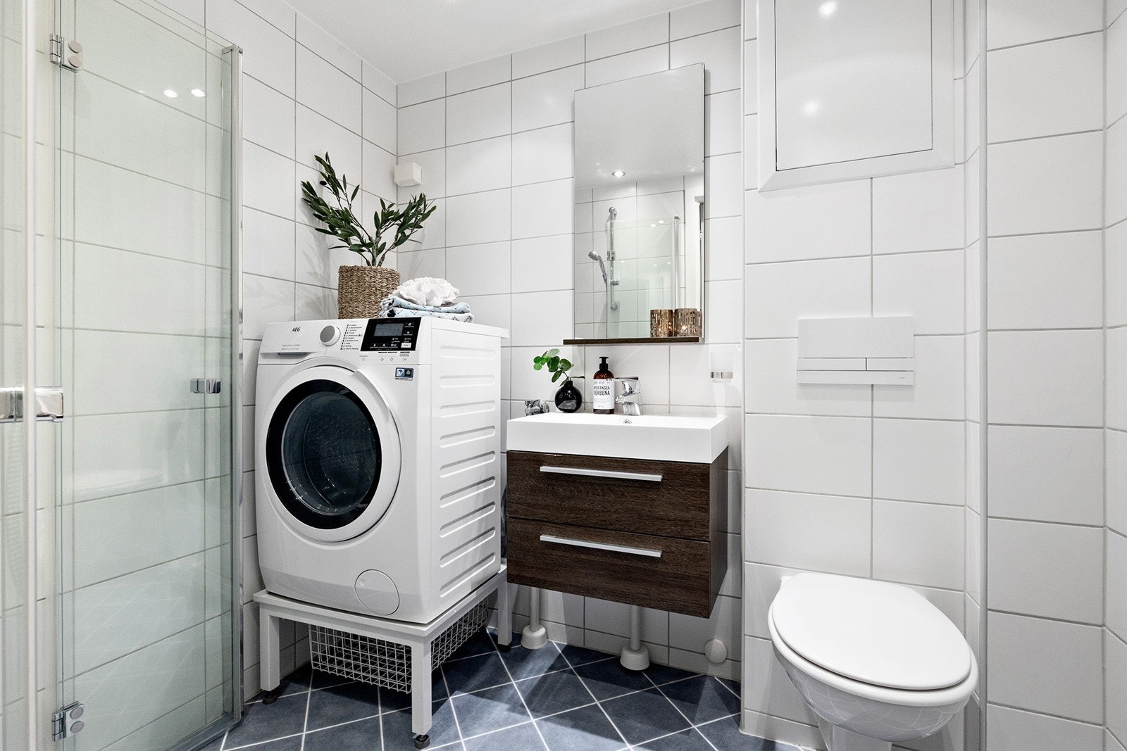 Flislagt bad med opplegg for vaskemaskin og praktiske oppbevaringsløsninger. Galleribilde