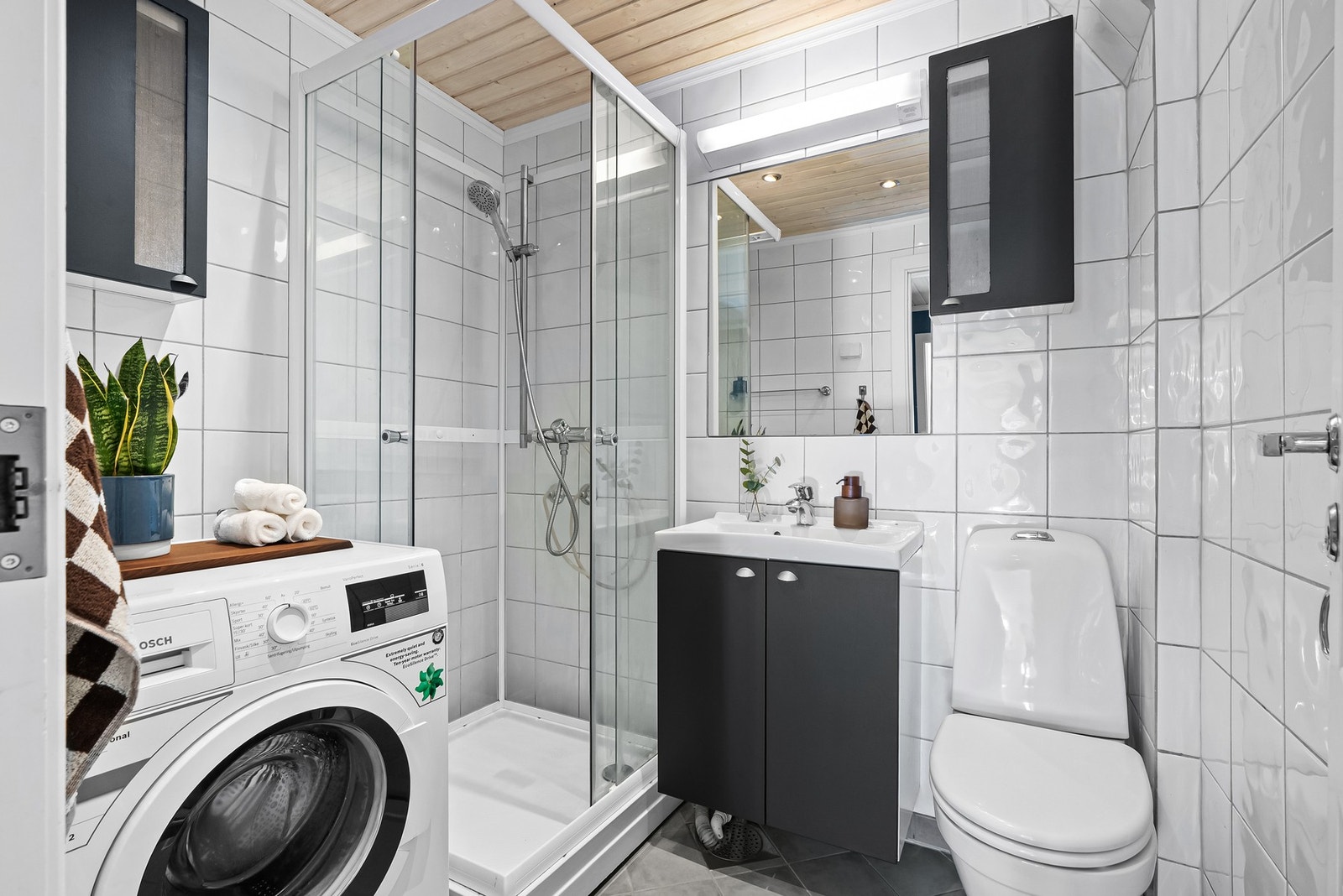 Badet har gulvvarme og downlights i himlingen. Innredningen består av servantskap med heldekkende servant, gulvmontert klosett og dusjkabinett med skyvedører. Galleribilde