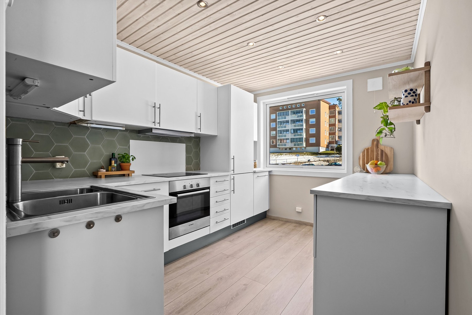 Pent kjøkken plassert i eget rom med adkomst fra entrè. Innredningen fra IKEA har lyse glatte fronter og benkeplate i laminat. Her er det godt med skapplass. Galleribilde