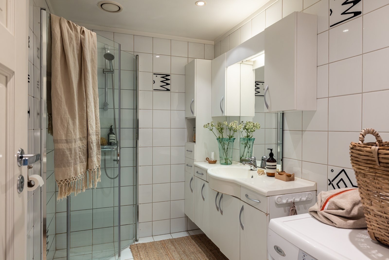 Badet er utstyrt med veggmontert toalett, dusjhjørne med vegger/dører i herdet glass, servant med skap, samt speil og belysning. Det er i tillegg montert praktisk opplegg for vaskemaskin. Galleribilde