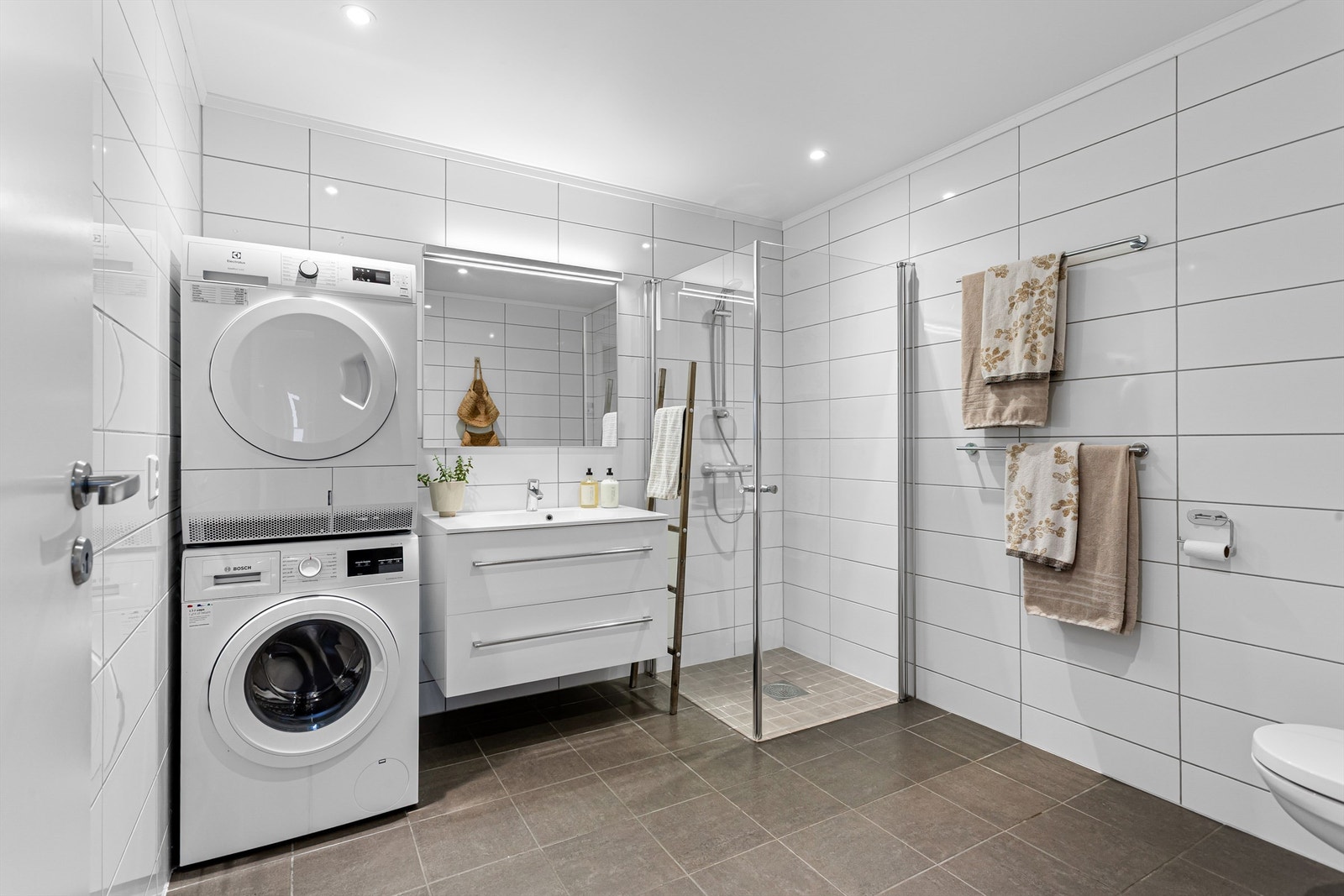 Stor bad. Flislagt gulv med gulvvarme. Downlights i himlingen. Innredet med vegghengt servantskap med skuffer og ovenpåliggende servant. Galleribilde