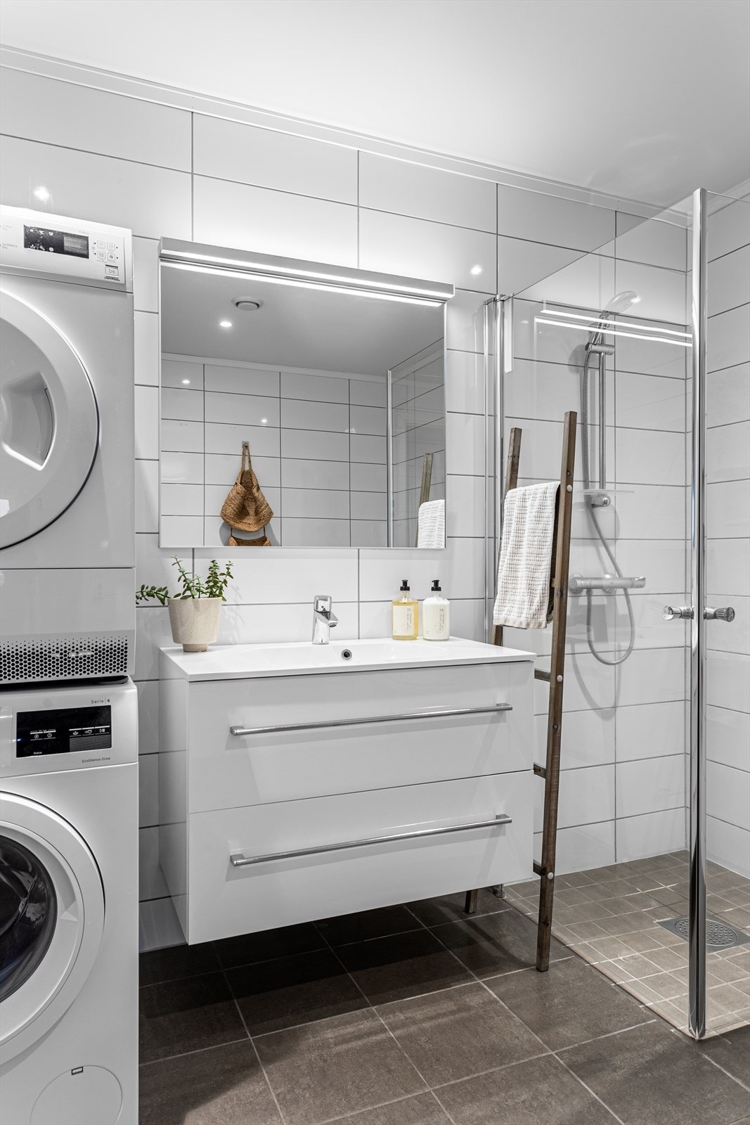 Nedsenket dusjsone i hjørnet med innfellbare glassdører. Opplegg for vaskemaskin og tørketrommel. Galleribilde