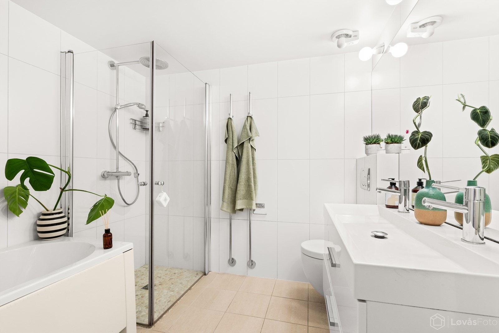 Delikat flislagt baderom innredet med dobbel servant med underskap, speil, badekar samt separat dusjløsning. Galleribilde