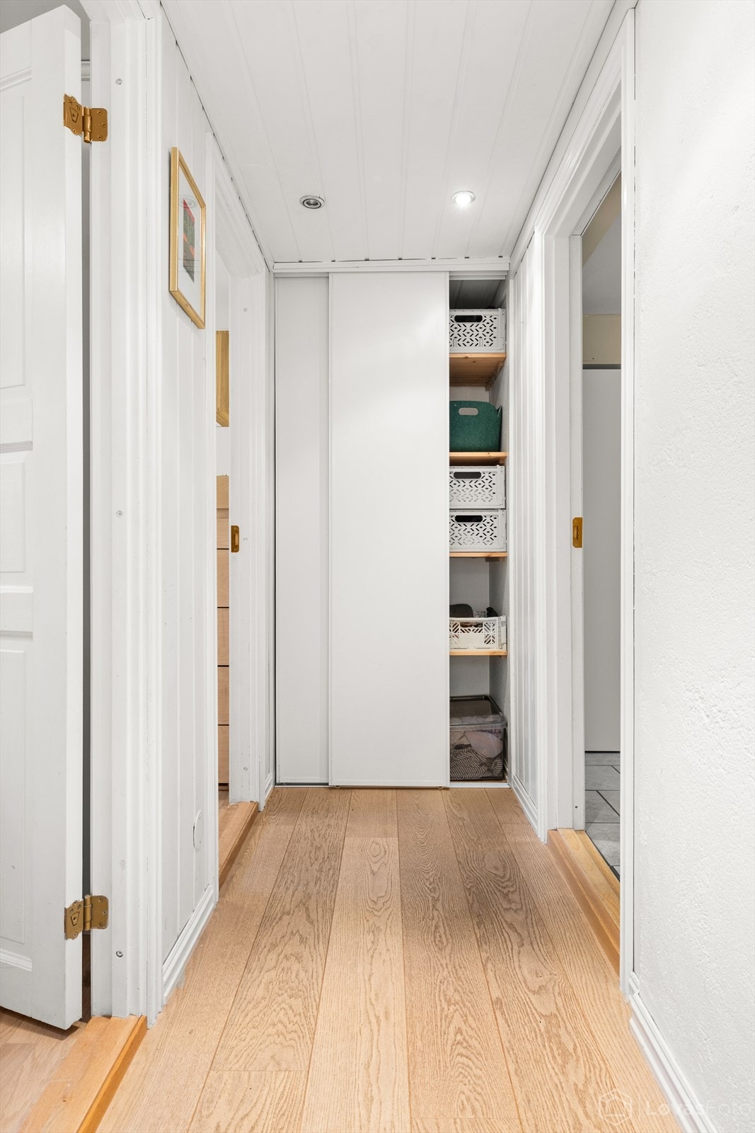 Fra trappen kommer man ned til en praktisk mellomgang, her er det gode oppbevaringsmuligheter i integrert skyvedørsgarderobe. Alle rom i kjelleretasjen har elektrisk gulvvarme! Galleribilde