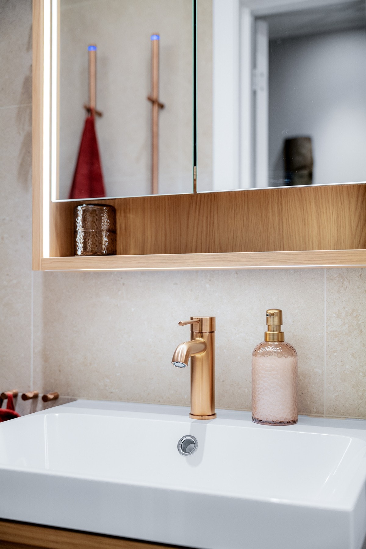 Flott baderomsinnredning med skuffer og ovenpåliggende servant, speilskap med integrert belysning over. Galleribilde