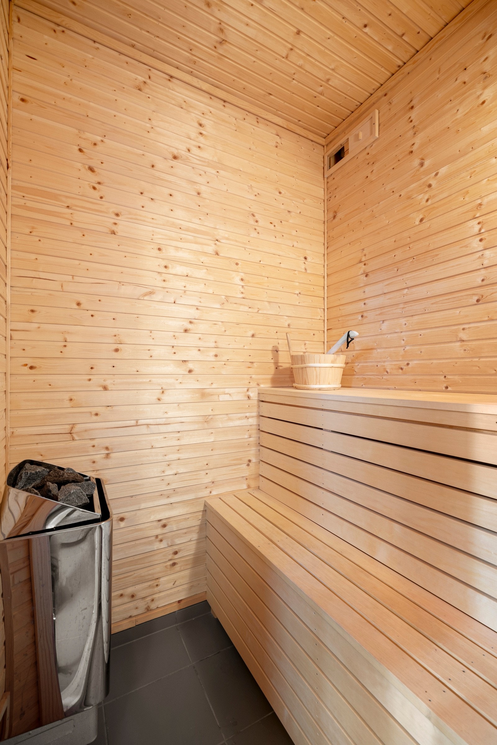 Badstuen er en del av badet, med gulvfliser, elektrisk ovn og plassbygde trebenker. Galleribilde