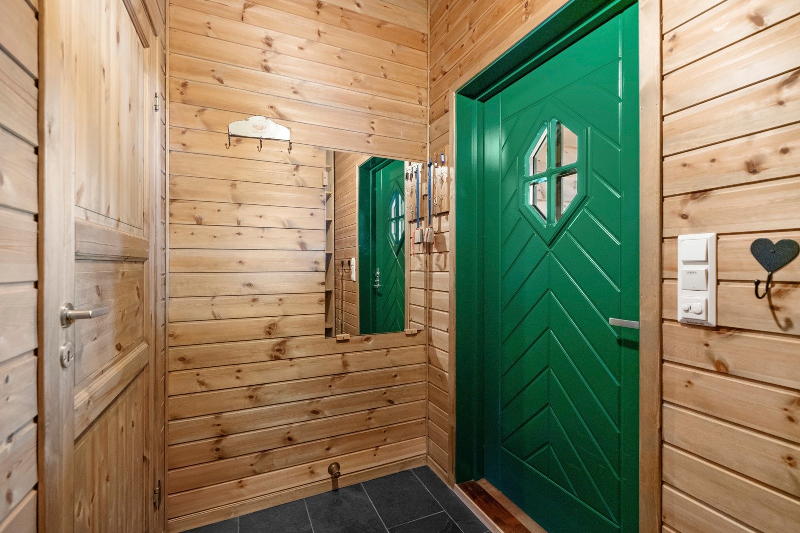 Ytterdøren er overbygd på terrassen, og vel inne passer det fint å innrede med knagger og skohyller i en liten entré. Galleribilde