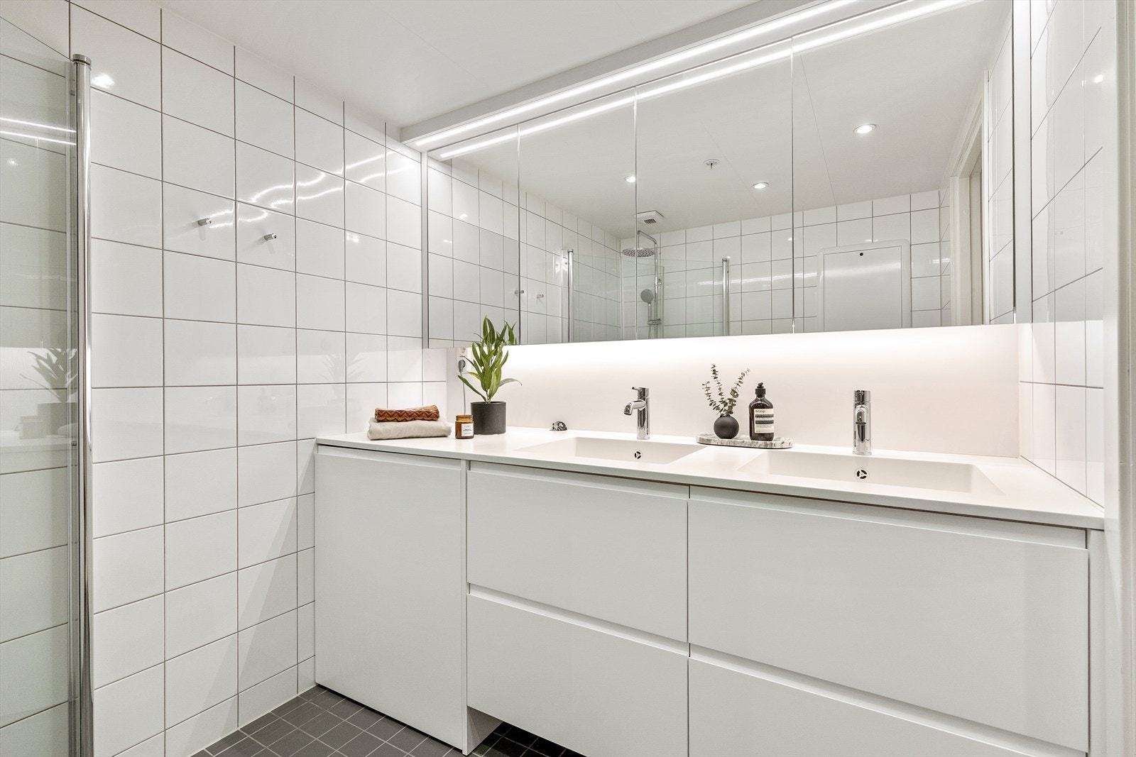 Innredningen består av et stilrent servantskap med benkeplate i Corian og to servanter. Over servantene er det montert et veggskap med speildører og integrert belysning. Innredning er plassbygd fra Elen Møbelstudio. Galleribilde