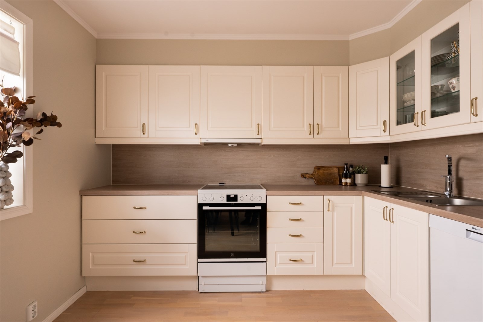 Kjøkkeninnredningen har lyse, profilerte fronter og to vitrineskap. Galleribilde