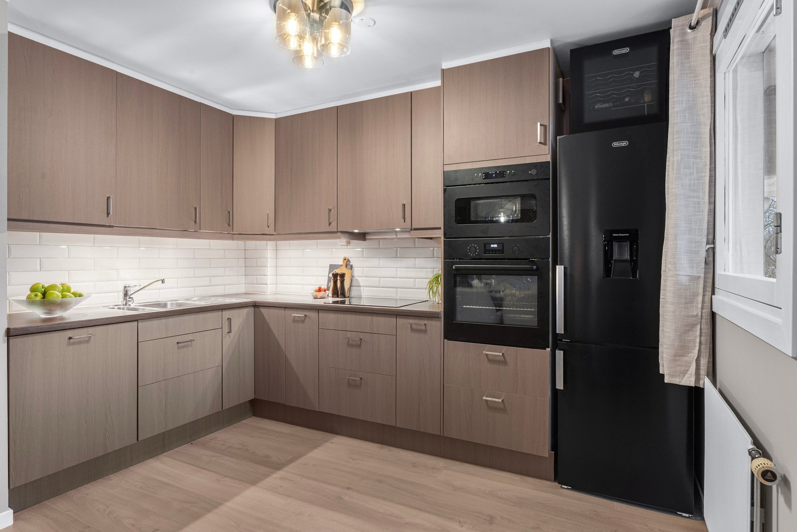 Stort kjøkken med moderne hvitevarer fra 2025, inkludert induksjonsplatetopp, integrert mikrobølgeovn og stekeovn, samt frittstående kjøl/fryseskap Galleribilde