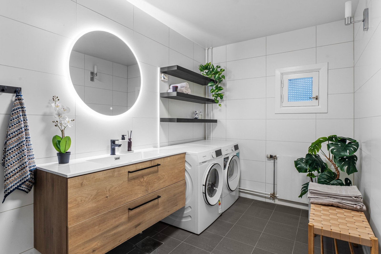 Romslig flislagt bad med gulvvarme og opplegg for vaskemaskin og tørketrommel Galleribilde