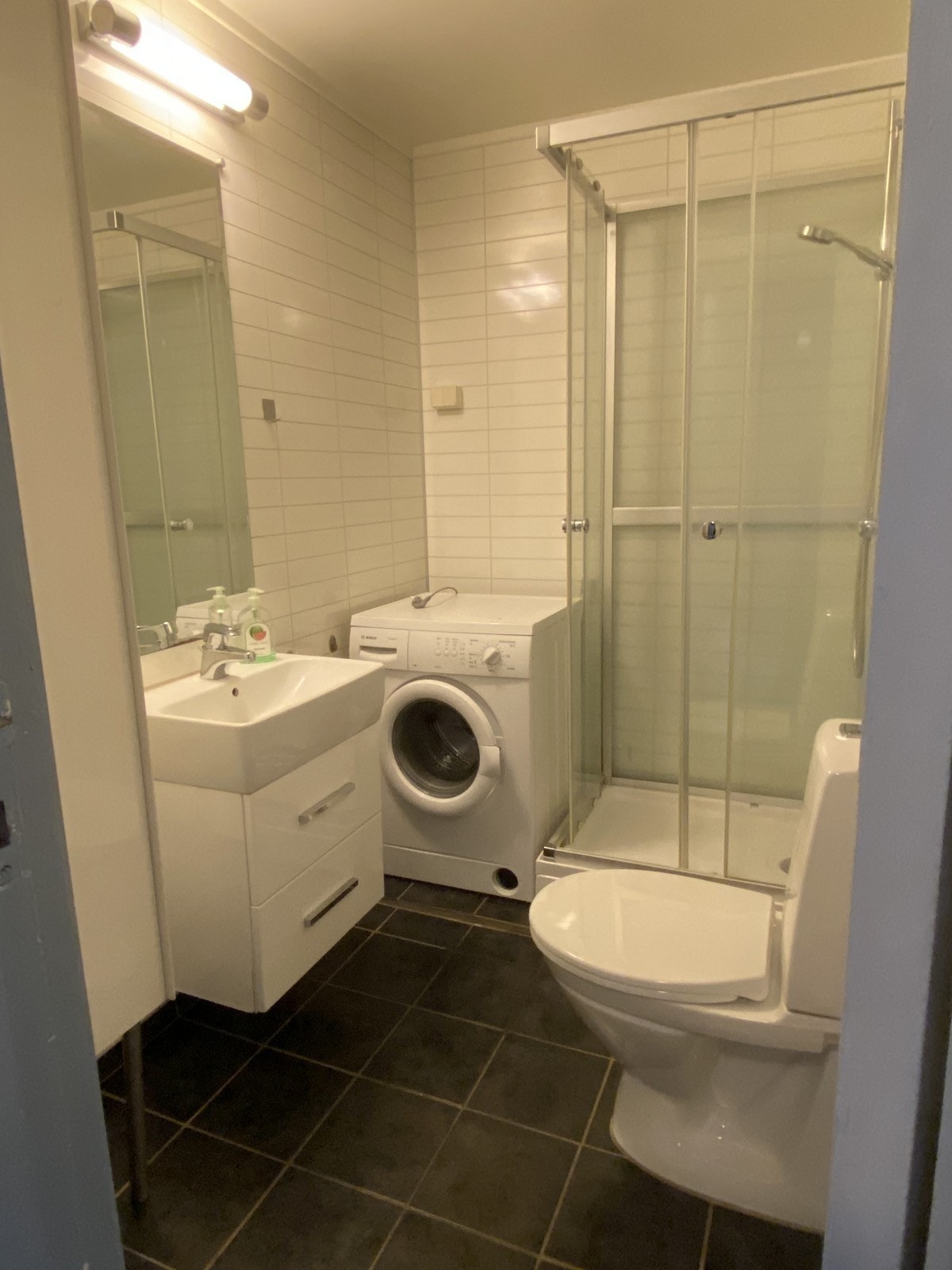 Bad/WC med dusjkabinett, gulvstående toalett og opplegg for vaskemaskin Galleribilde