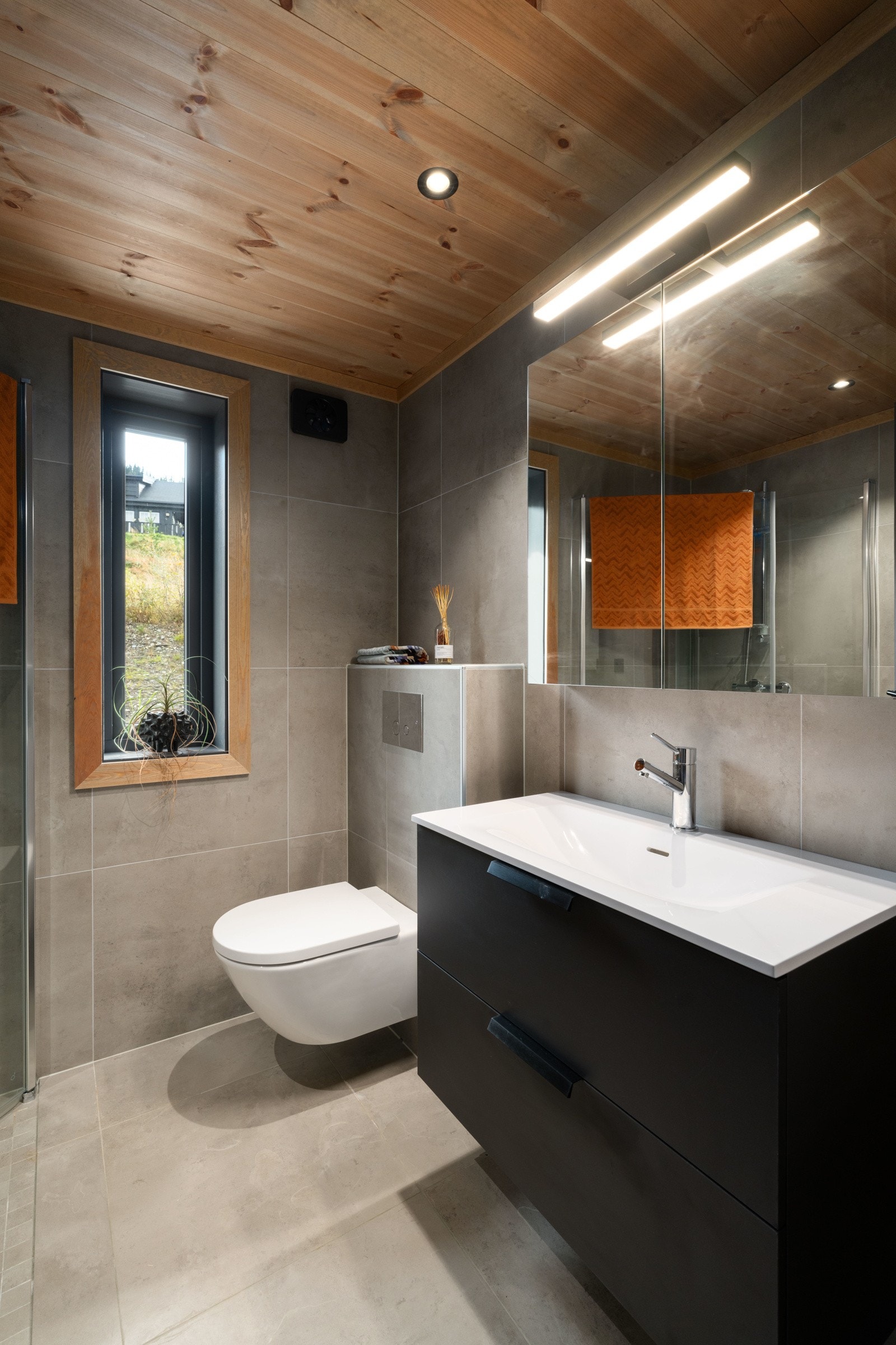 Gulvstående wc, rette dusjdører i glass ved dusj og dusjbatteri med garnityr og håndholdt dusj. Galleribilde