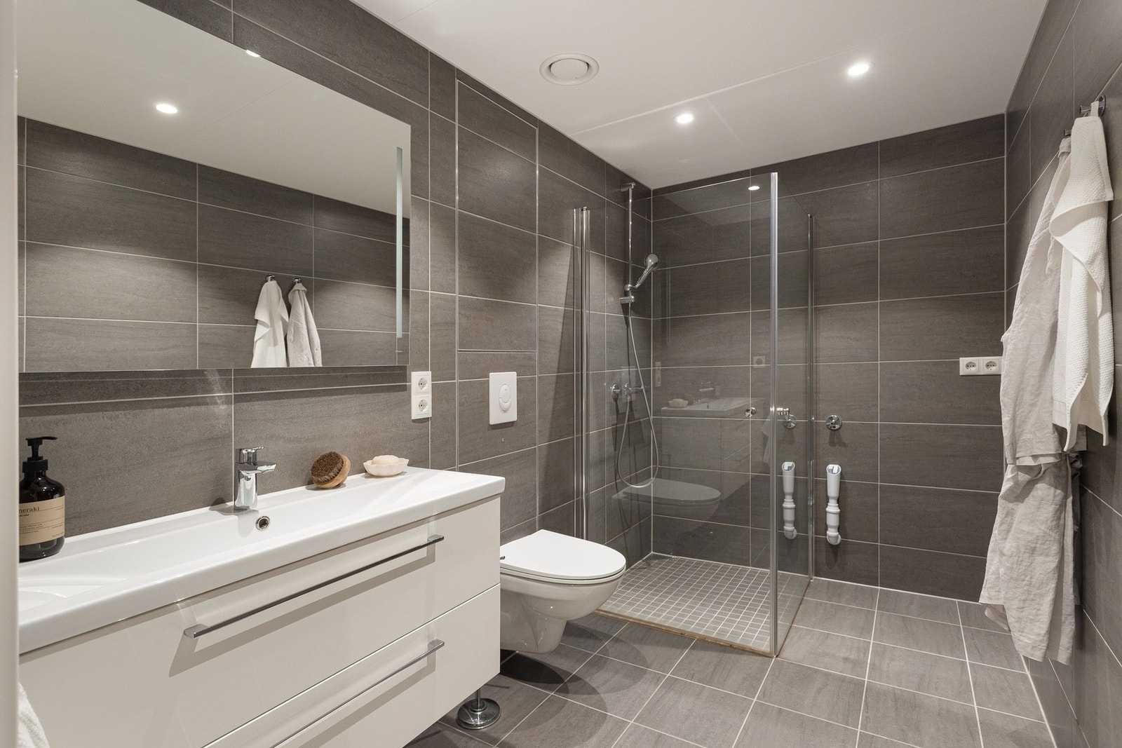 Delikat flislagt baderom med vannbåren gulvvarme og downlights i himling. Det er opplegg for vaskemaskin og plass til tørketrommel. Galleribilde