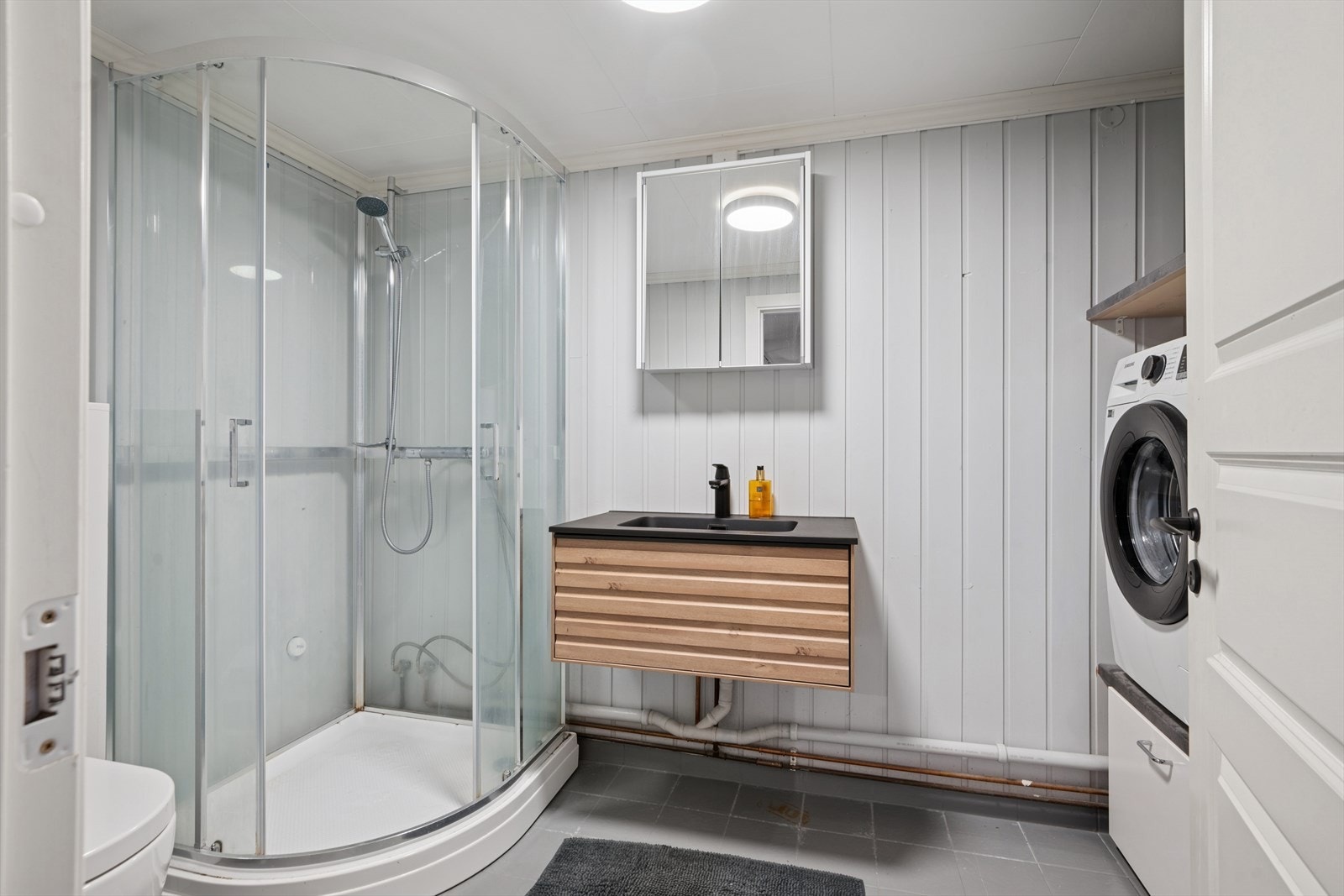 Plass og opplegg til vaskemaskin med skuffeseksjon under og hylle over vaskemaskin. Varme i gulv. Galleribilde