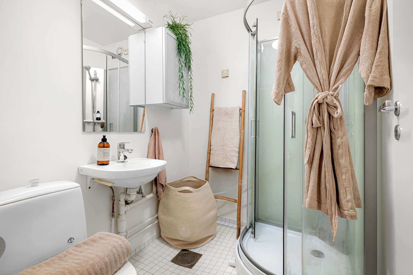 Baderommet er utstyrt med vegghengt servant med speil og belysning over, vegghenht skap, dusjkabinett (nytt i 2024) og gulvstående toalett. Galleribilde