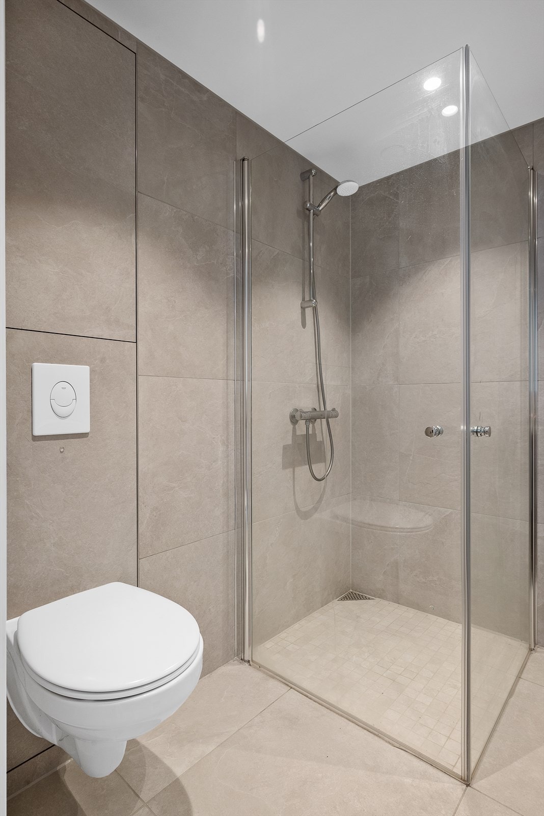 Badet har fått tilstandsgrad 0 av takstmannen og byr på veggmontert toalett, dusjhjørne med innfellbare dusjvegger og spotter i tak. Galleribilde